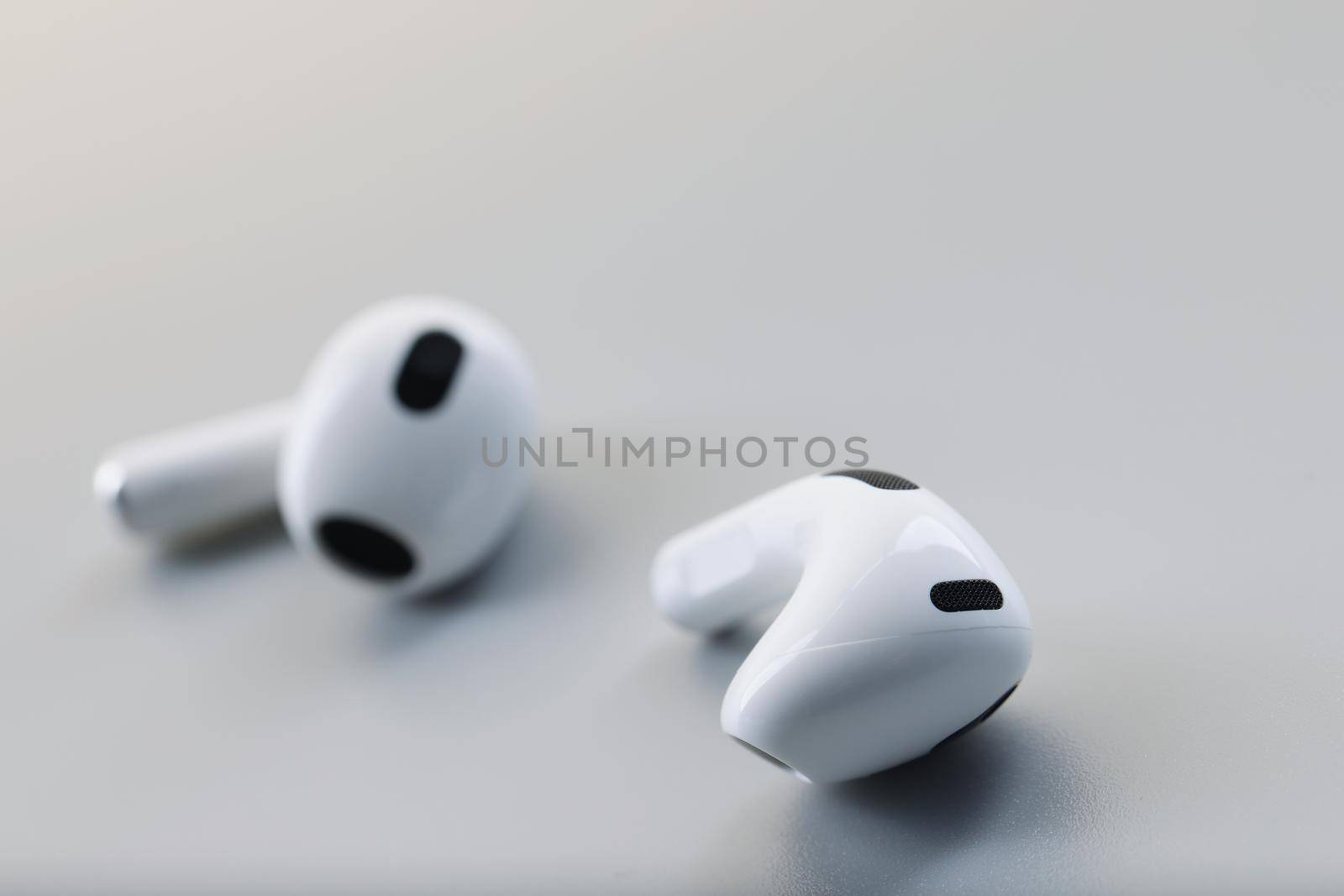 White wireless bluetooth earbuds on a gray background. Fashion phone accessory, headphone noise reduction