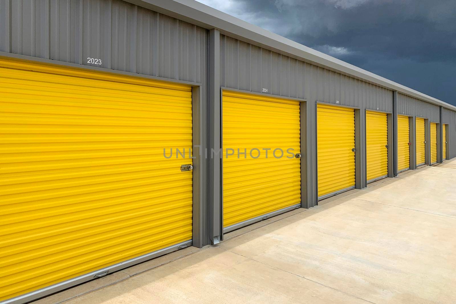 Exterior of a commercial warehouse with yellow roller doors, garages, self storage facilities. by Khosro1