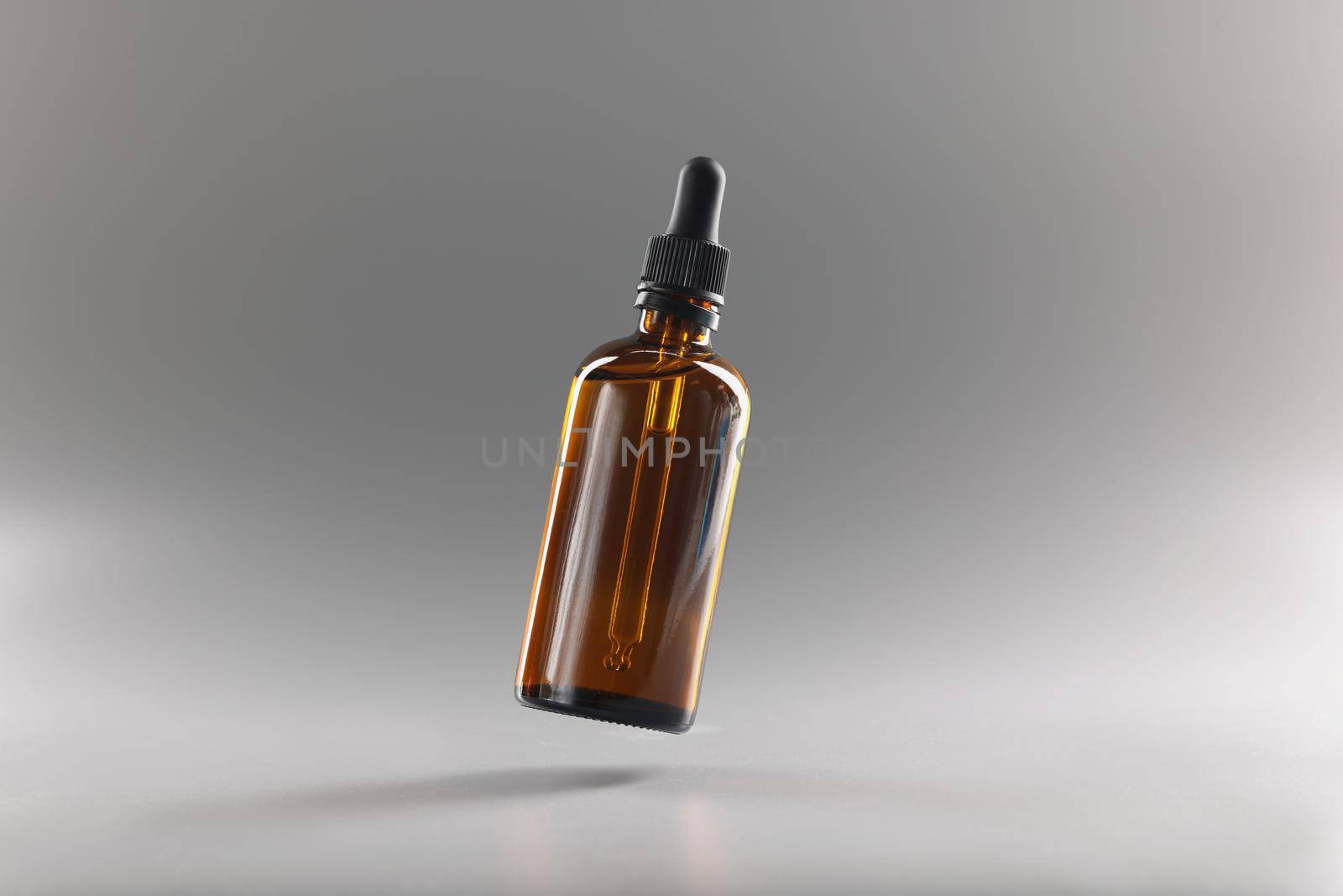 Brown transparent bottle with a pipette on a gray background, close-up. Dropper for medicines. Drop dispenser