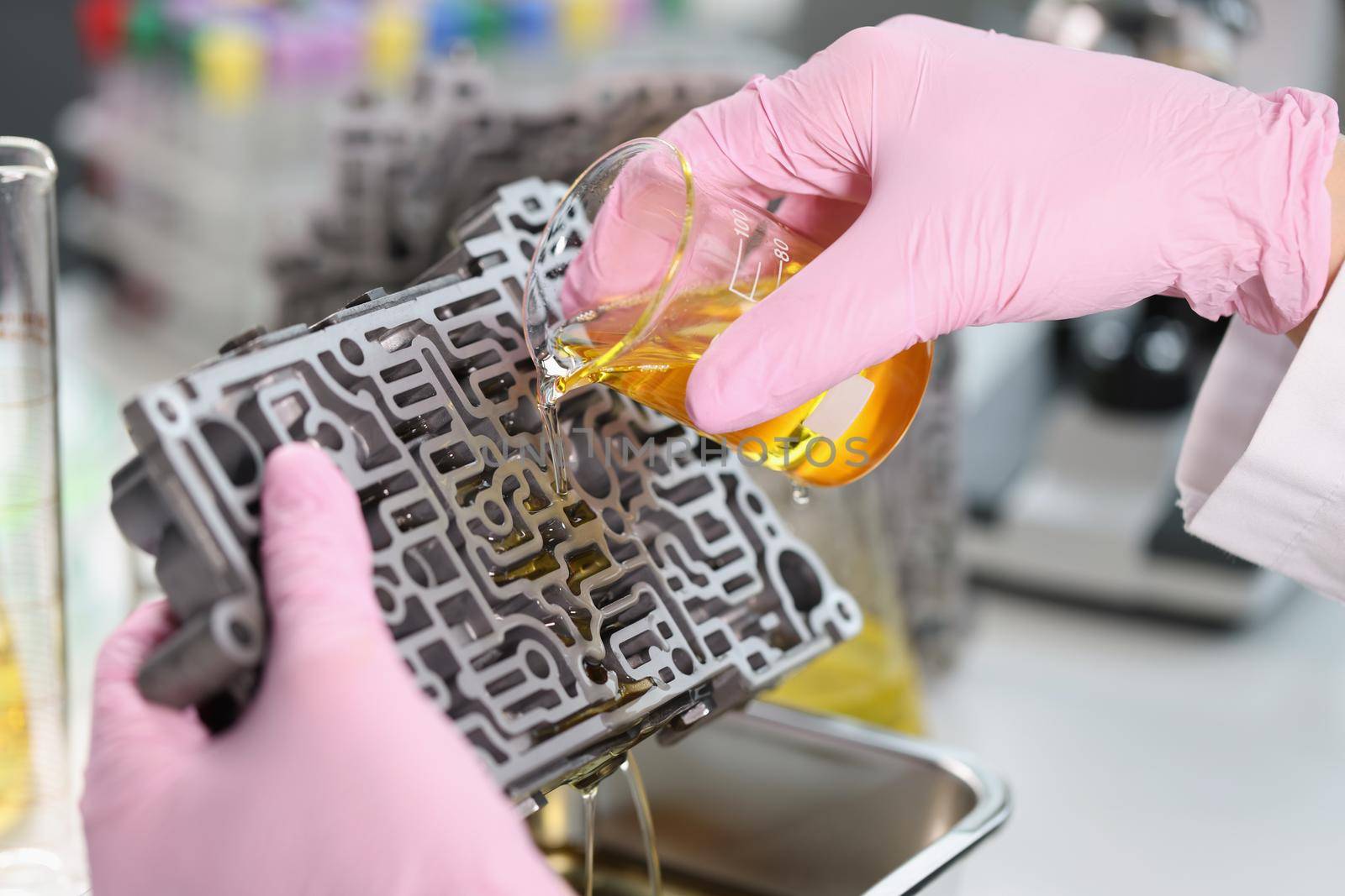The laboratory assistant pours a yellow liquid on the metal, close-up. Chemical reaction, scientific experiment