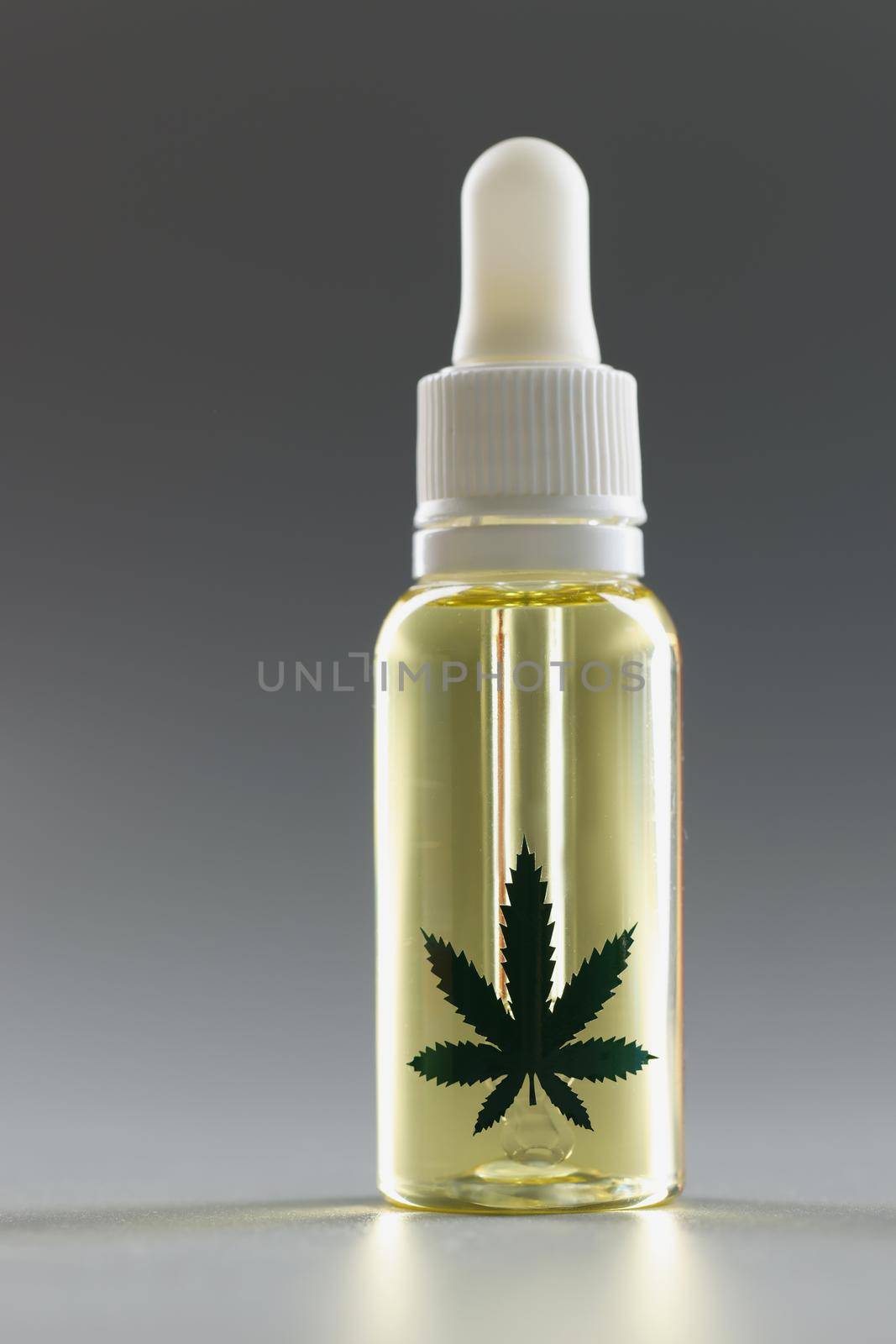 Hemp oil with a dispenser on a gray background, close-up. Pharmaceutical medical drug with cannabis, dropper