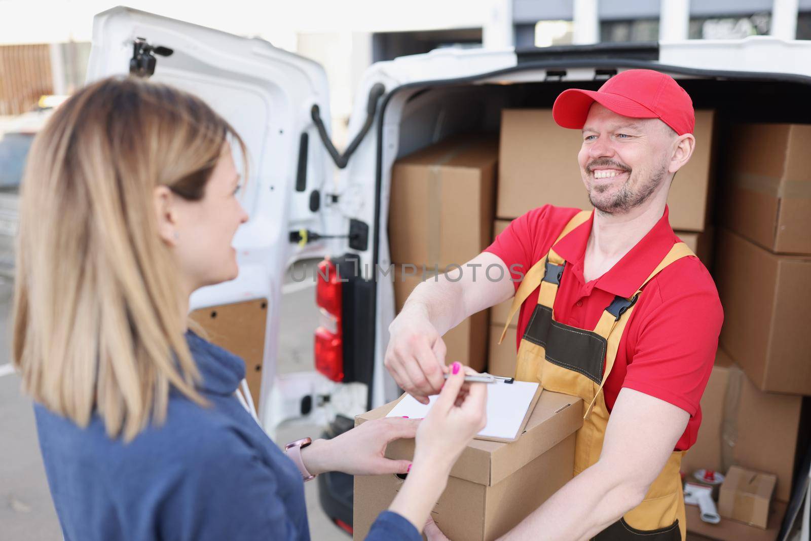 Happy woman on the street receives a parcel from the courier. Targeted delivery of goods during a pandemic