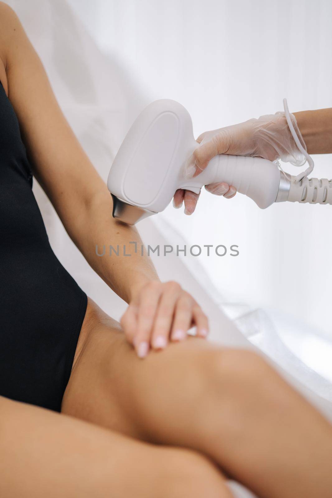 Cosmetology. Beautiful woman receiving laser hair removal procedure at beauty salon. Beautician doing beauty treatment for female arm at spa salon. Protective glasses. Close-up by Gritsiv