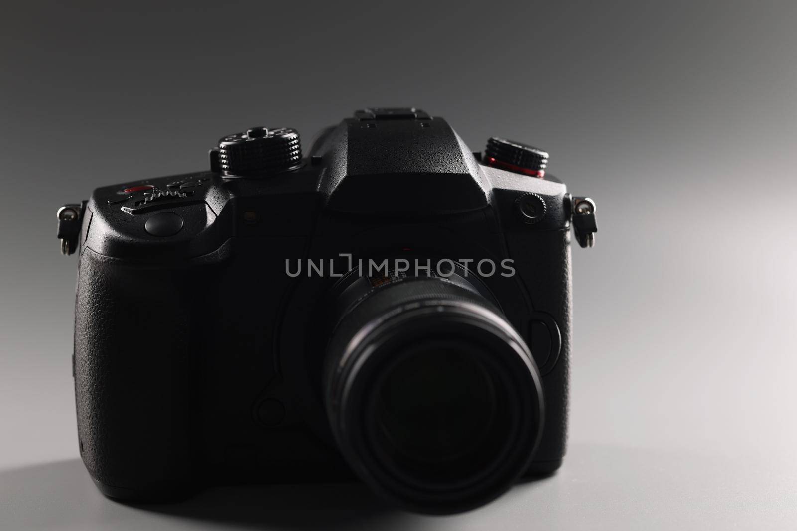 Black photo camera on a gray background, close-up. Digital device for photography, professional equipment for photographer