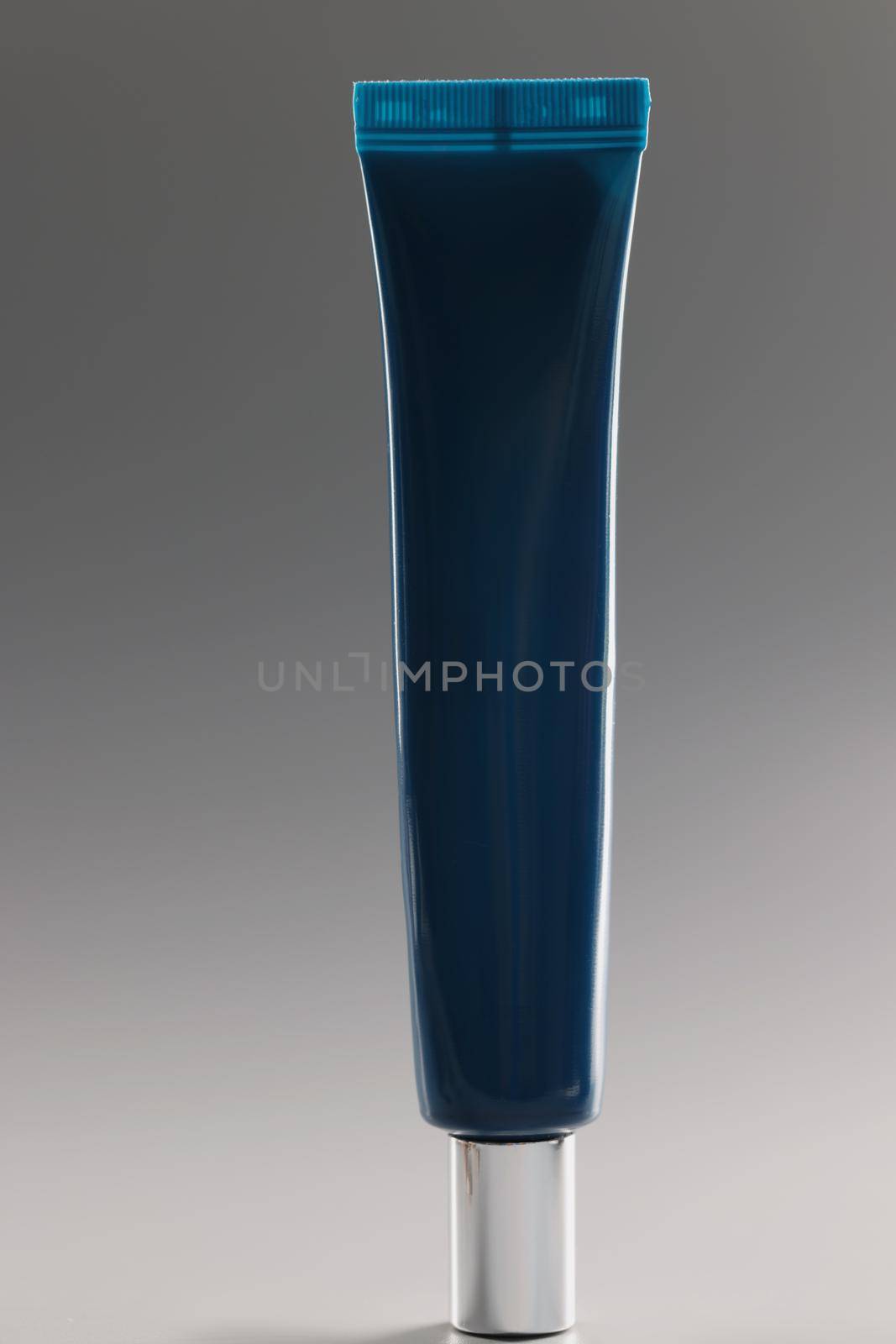 Blue tube with cream on a gray background, close-up. Facial cosmetics, non-comedogenic, skincare and makeup products