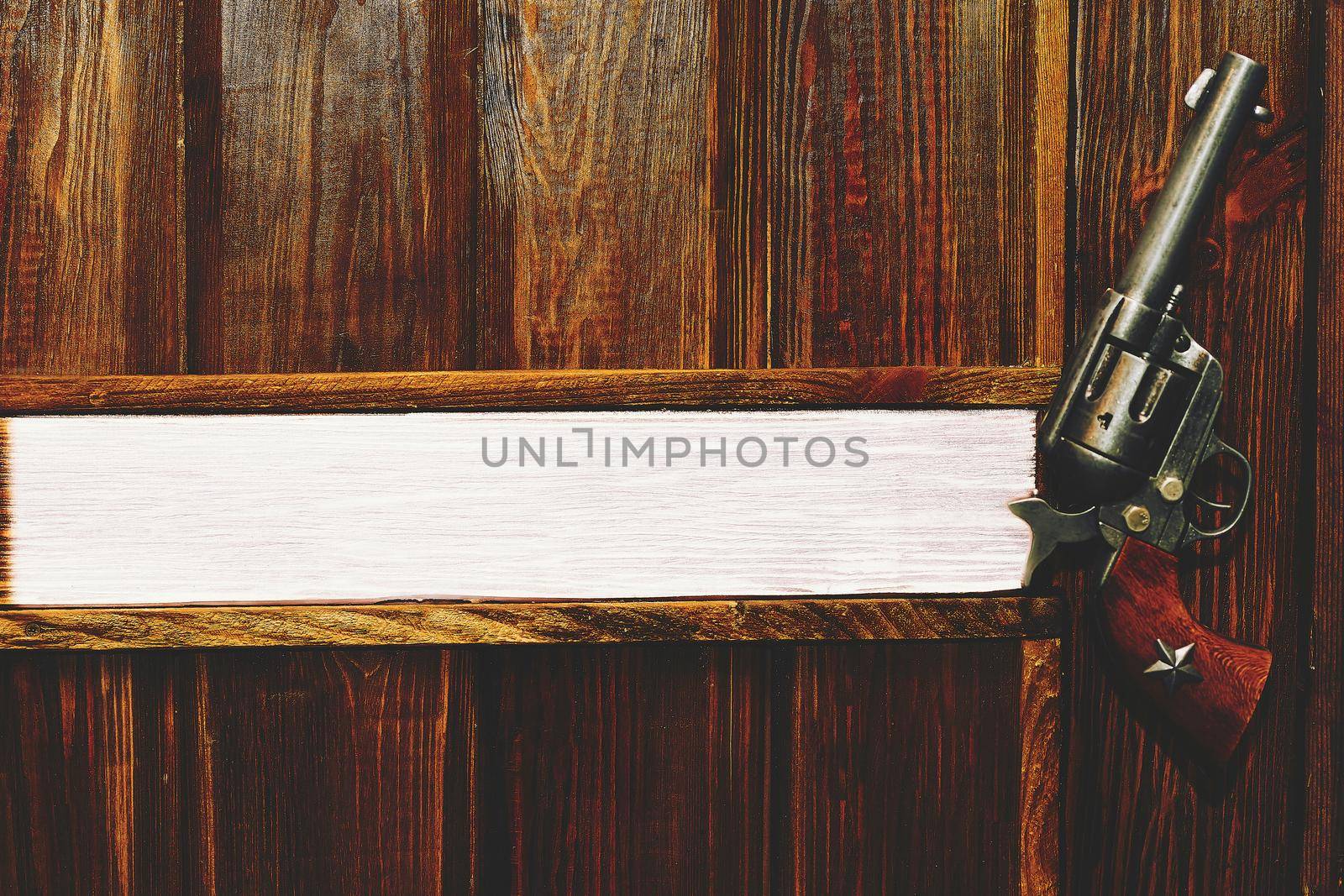 a pistol with revolving chambers enabling several shots to be fired without reloading. Cowboy gun revolver on a light brown wooden wall . Space for text. Boss's office