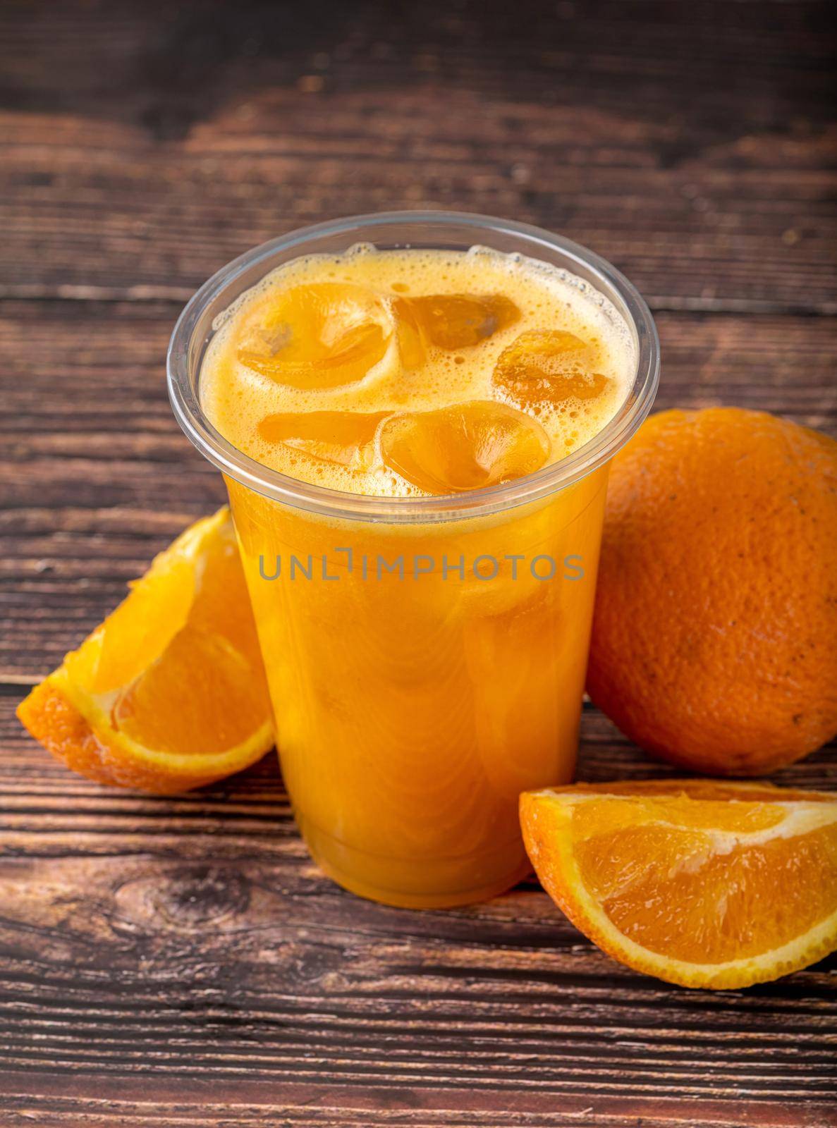 Freshly squeezed orange juice with ice cubes on wooden table