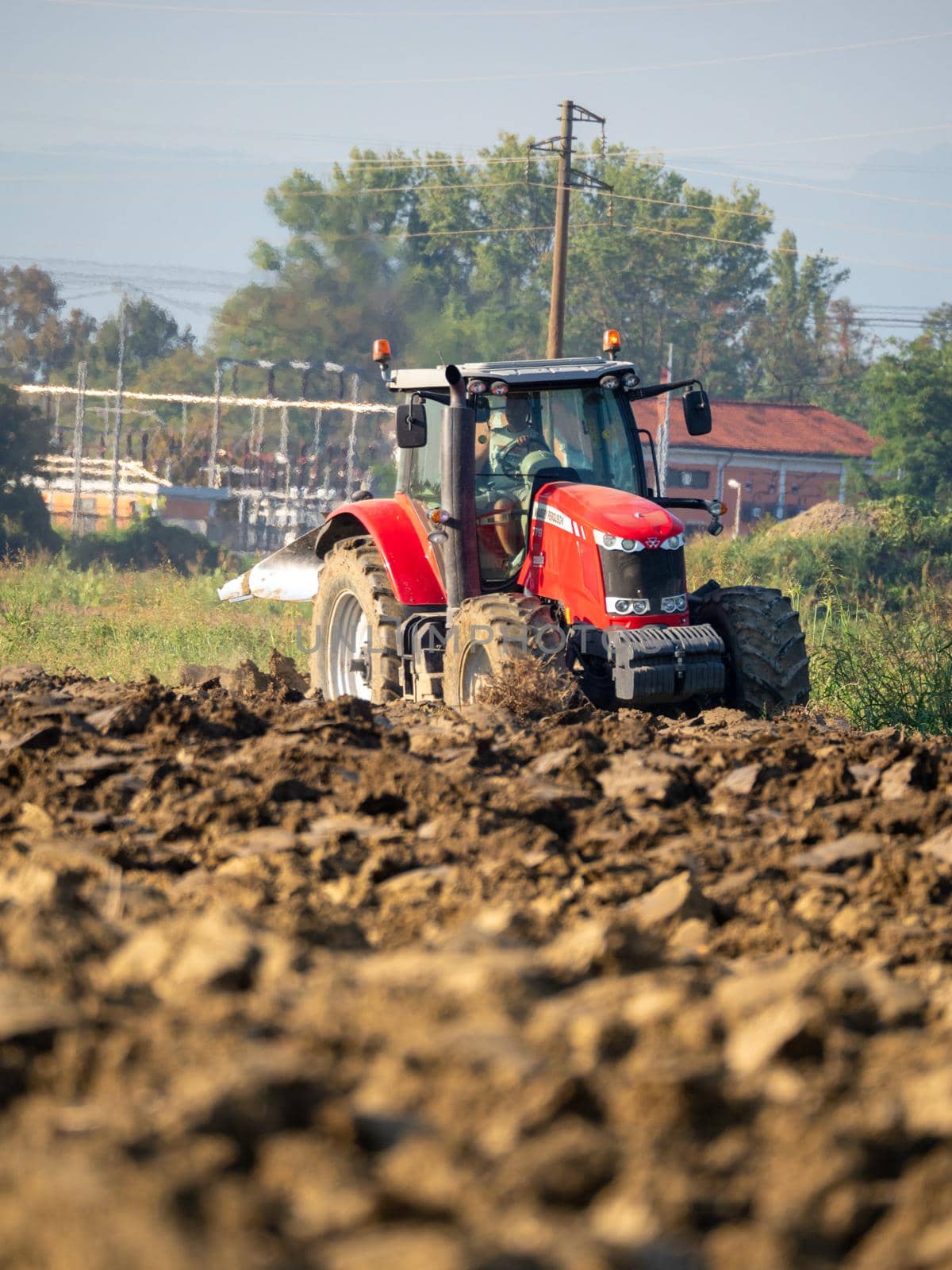 4k video of red tractor plowing the land in the countryside.