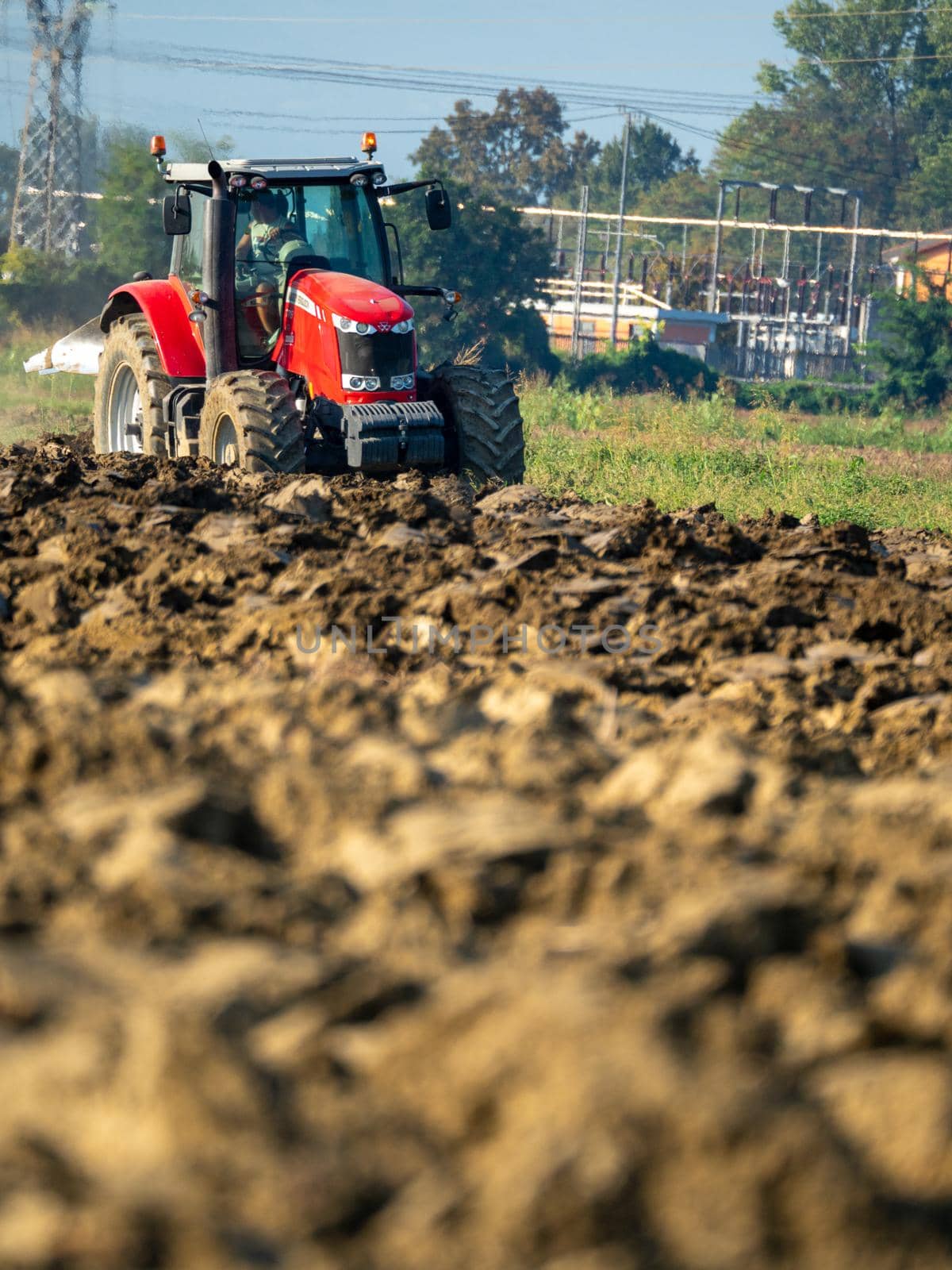 4k video of red tractor plowing the land in the countryside.