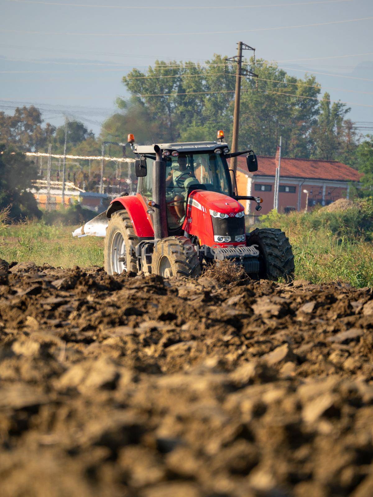 Farmer driving tractor plowing land at the end of the summer season by verbano