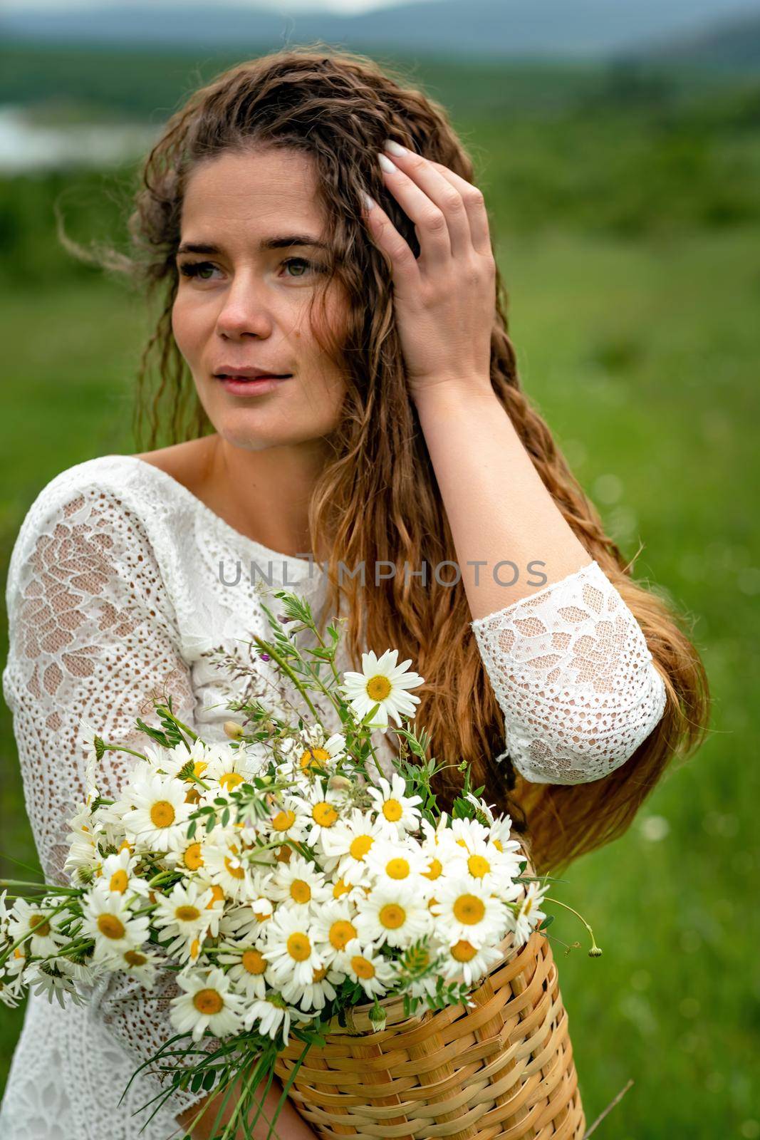 A middle-aged woman holds a large bouquet of daisies in her hands. Wildflowers for congratulations.