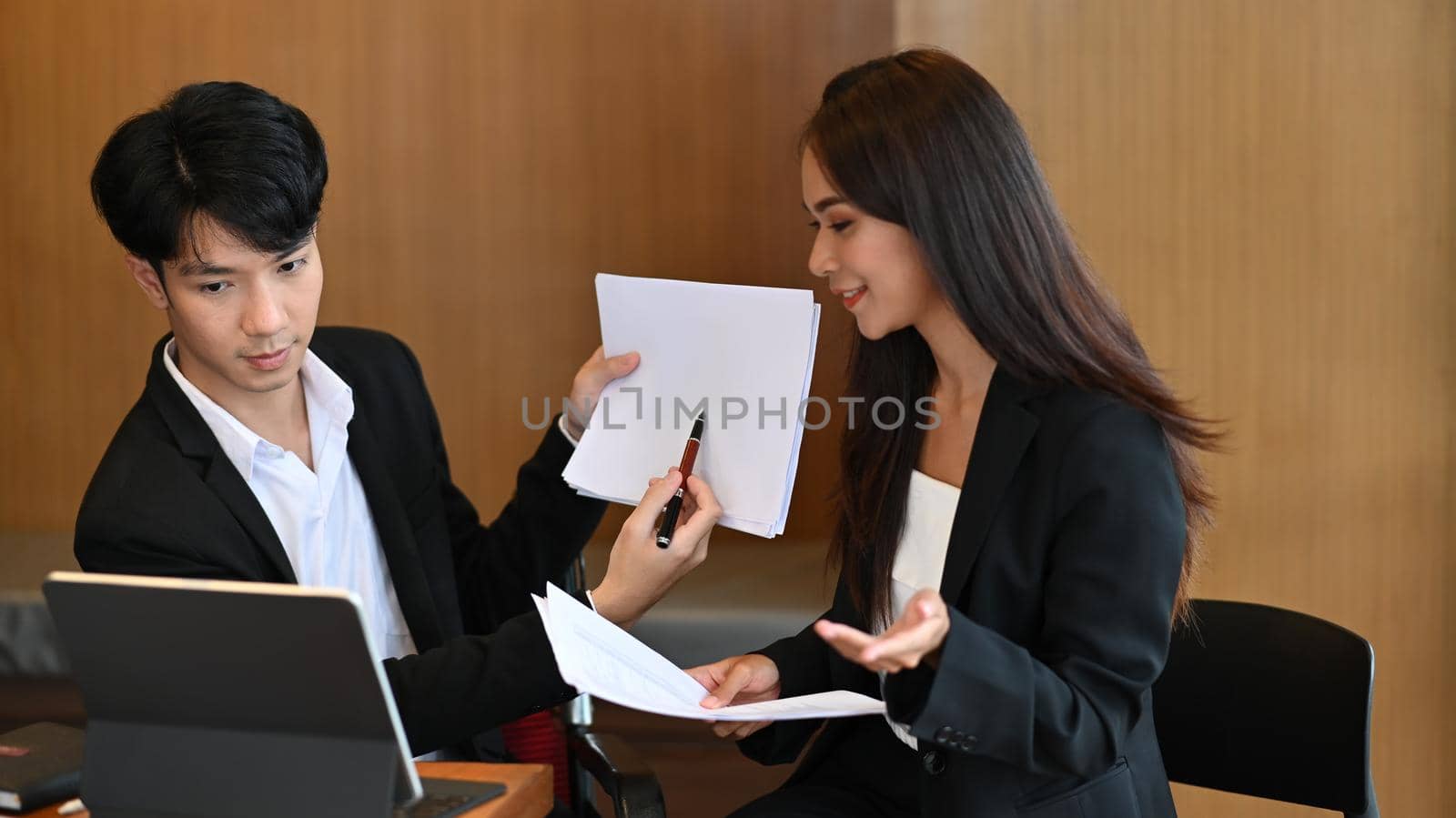 Two business colleagues talking and pointing on financial report during video conference.