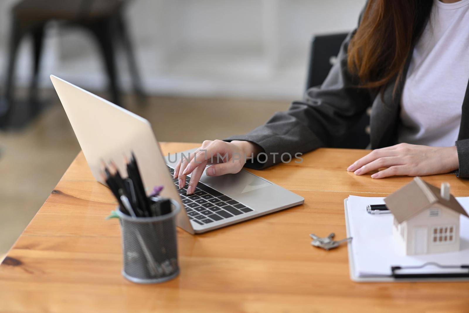 Real estate agent working with laptop computer in her office room. Mortgage and real estate investment.