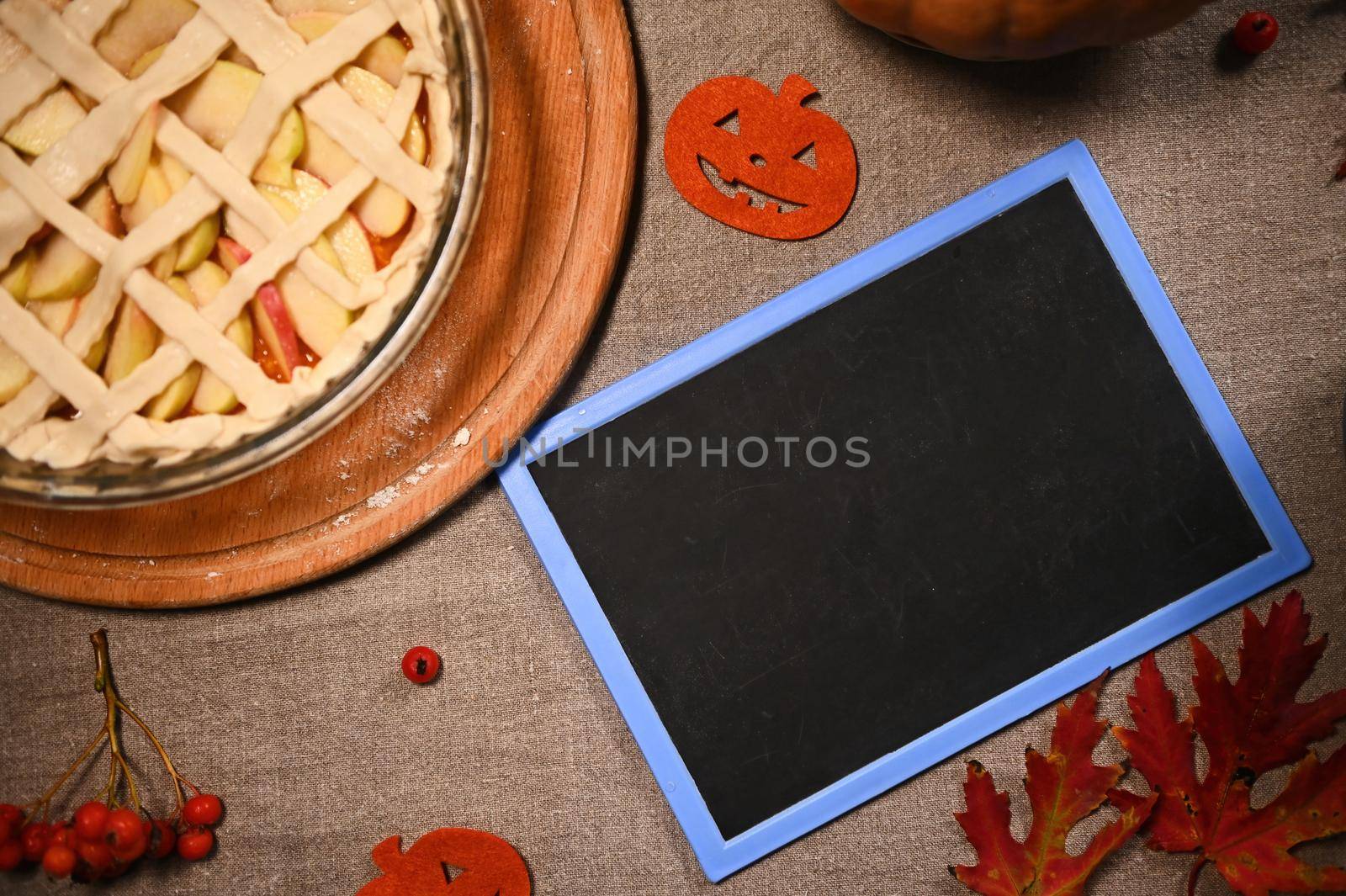 Top view freshly baked Thanksgiving pie with pumpkin and apples and crispy crust lattice and blackboard with copy space by artgf