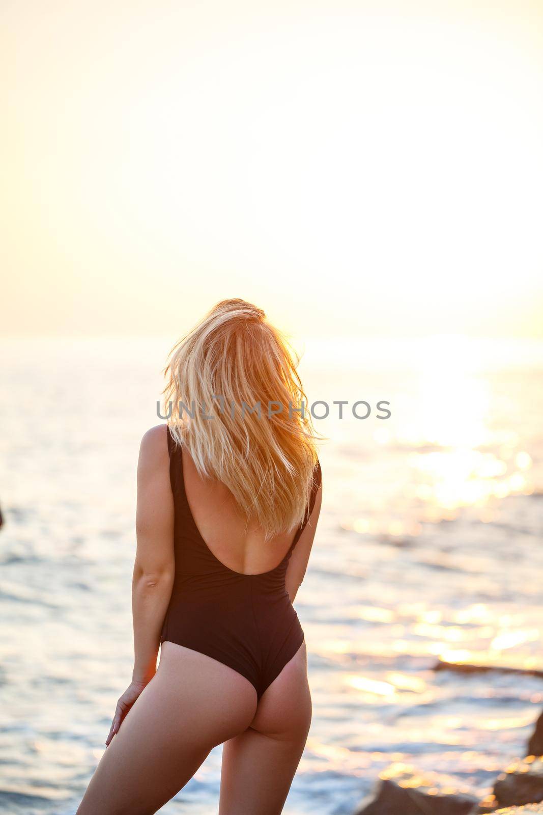 Young beautiful woman enjoying the breeze on the beach. Portrait of a carefree girl relaxing at the sea. Beautiful smiling woman enjoying the sun on the beach.