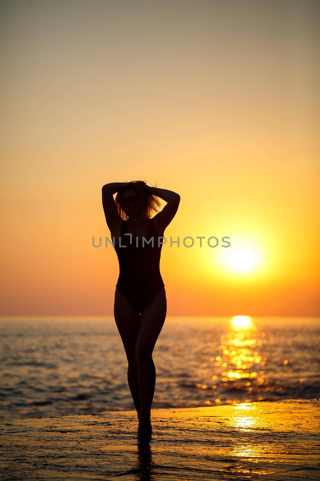 Silhouettes of a girl against the background of the sea and the setting sun. Selective focus by Dmitrytph