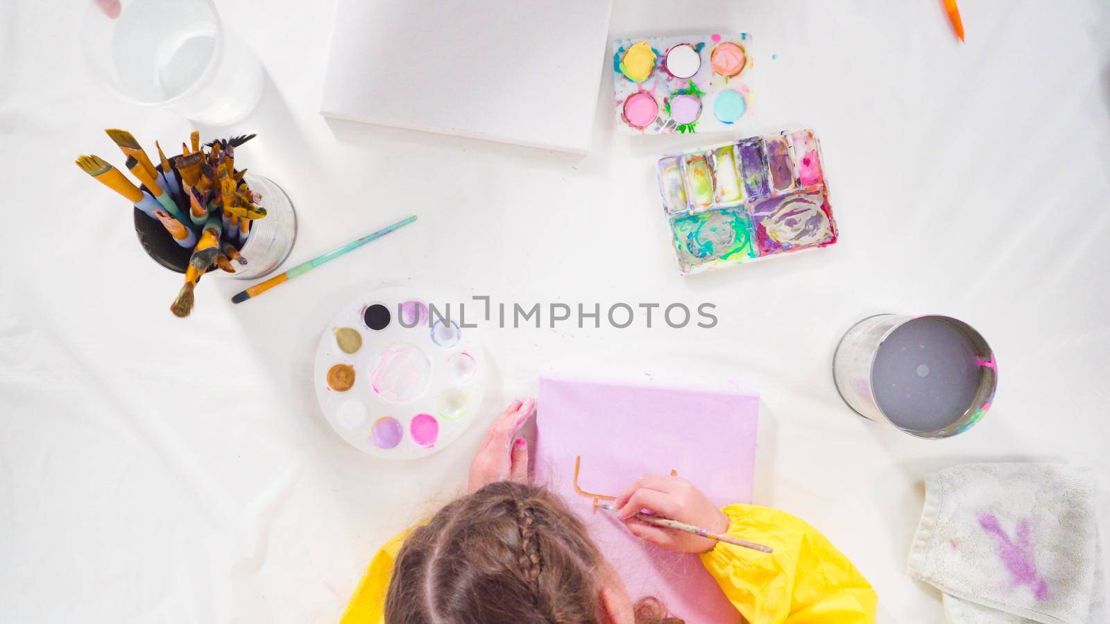 Flat lay. Little girl painting with acrylic paint on canvas with her mother for a distant learning art project.