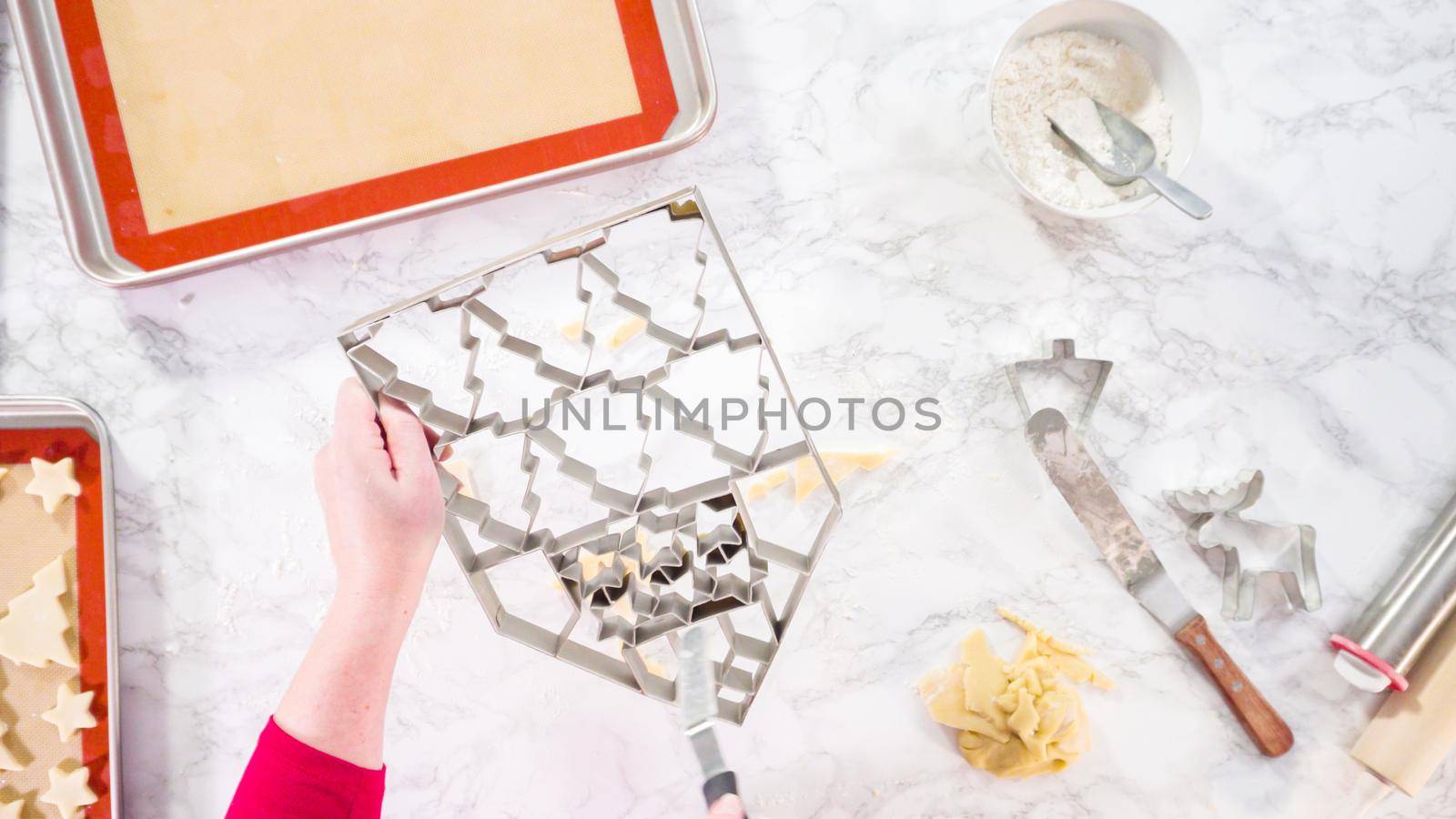 Flat lay. Cutting out sugar cookies with giant Christmas cookie cutter.