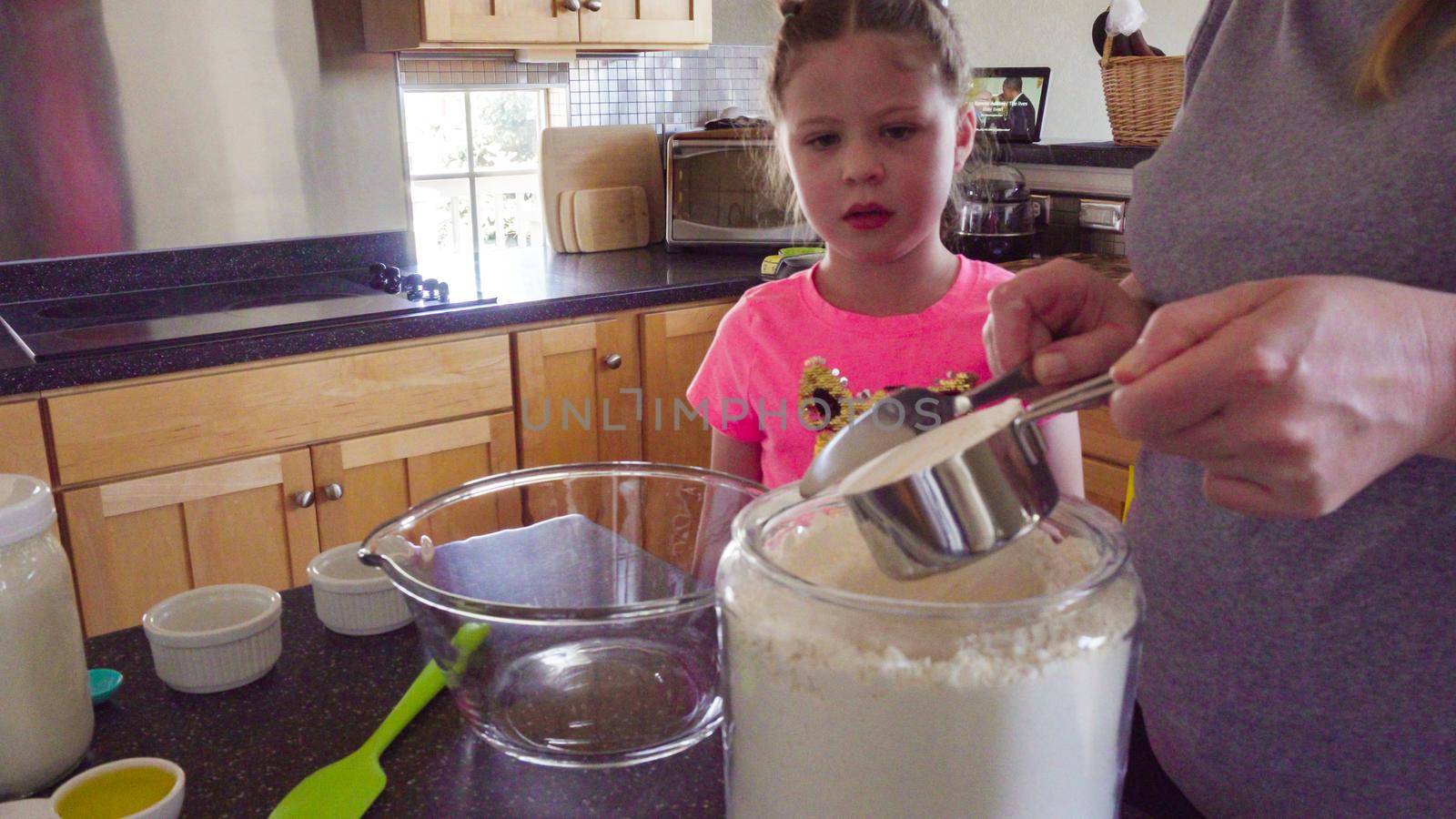 Little girl baking flatbread with her mother in the kitchen.