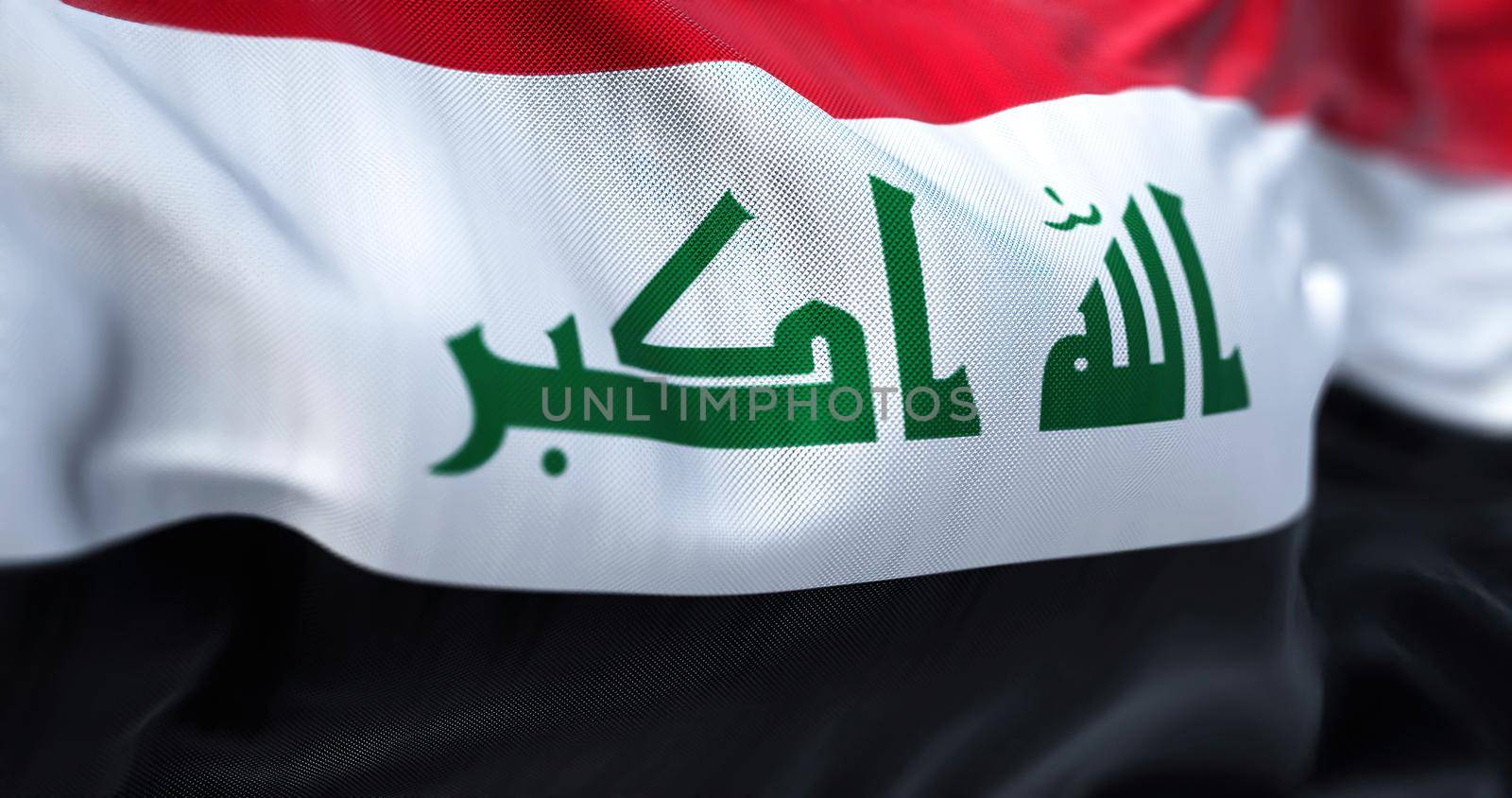 Close-up view of the Iraq national flag waving in the wind. The Republic of Iraq is a West Asian state. Fabric textured background. Selective focus