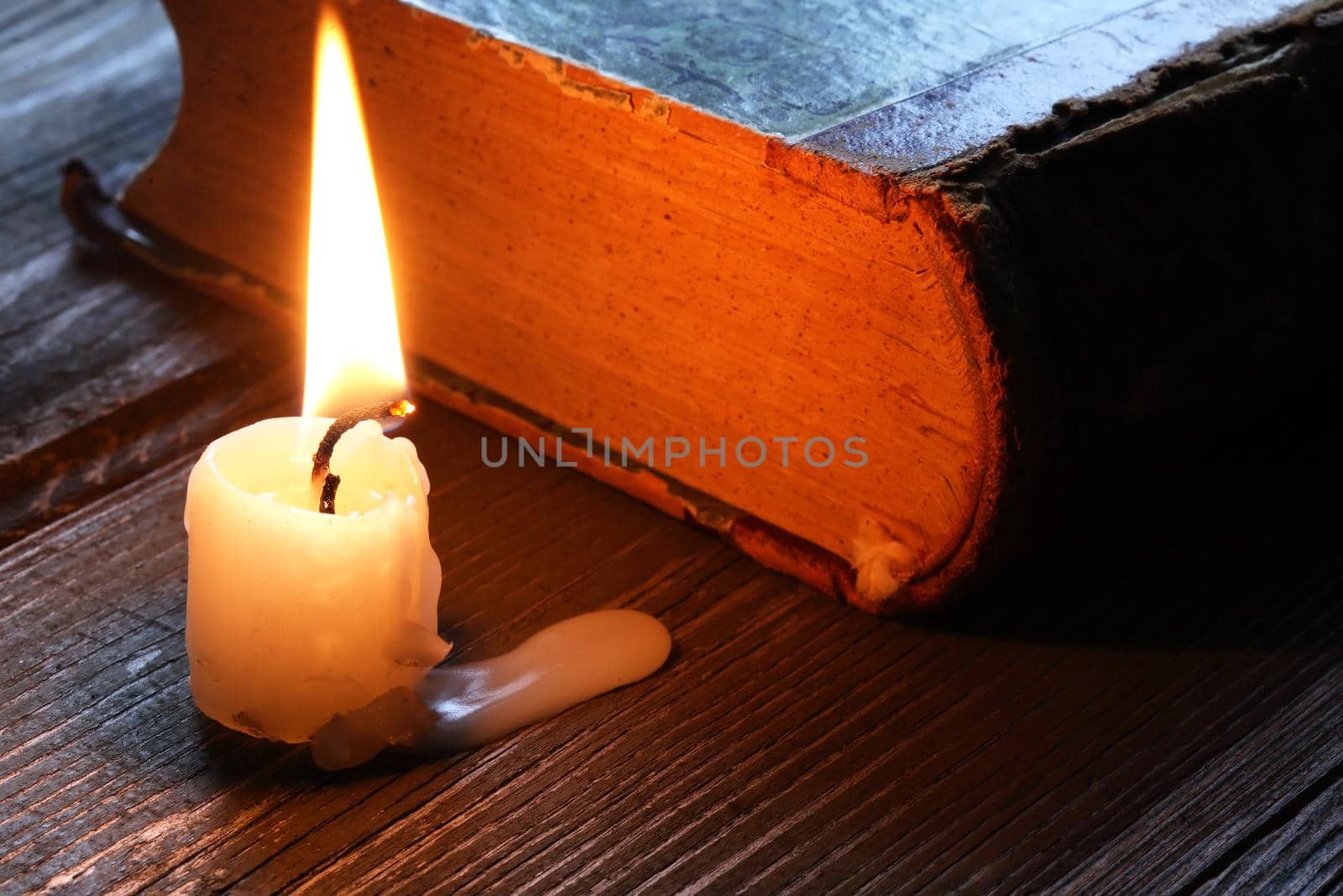 One lighting candle near old book on wooden table