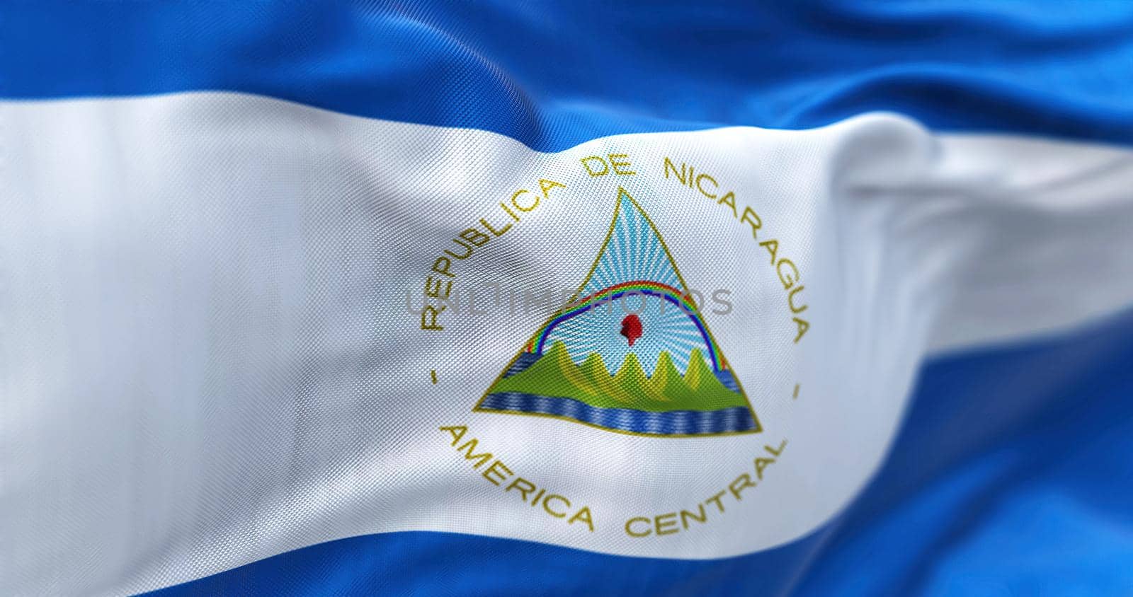Close-up view of the Nicaragua national flag waving in the wind. The Republic of Nicaragua is a State of Central America. Fabric textured background. Selective focus