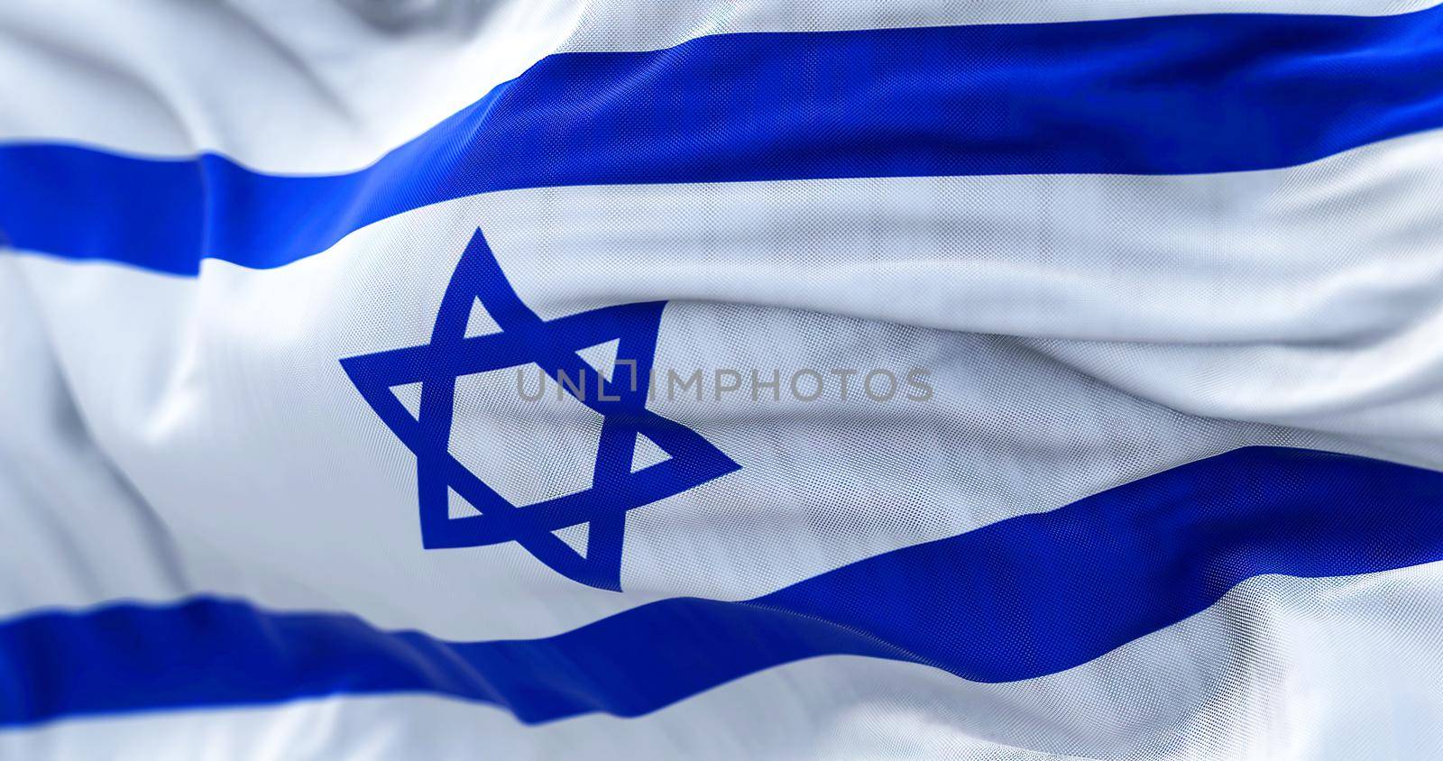 Close-up view of the Israel national flag waving in the wind. The State of Israel is a State of the Near East facing the Mediterranean Sea. Fabric textured background. Selective focus