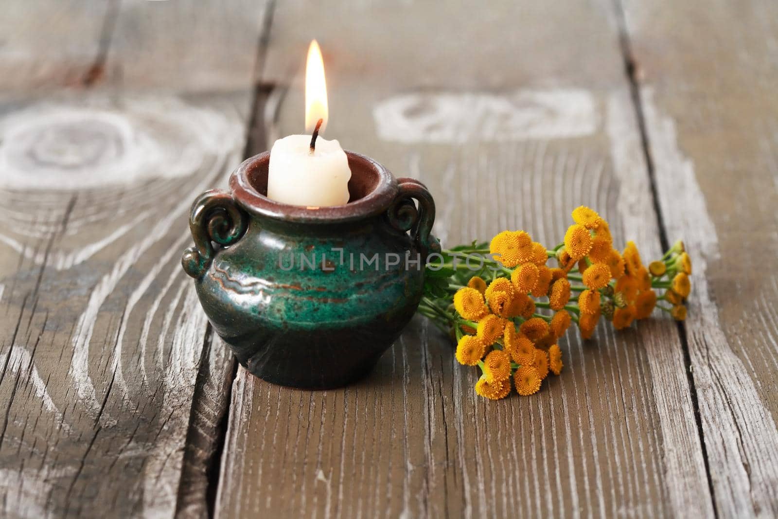 One lighting candle near bunch of yellow wild flowers
