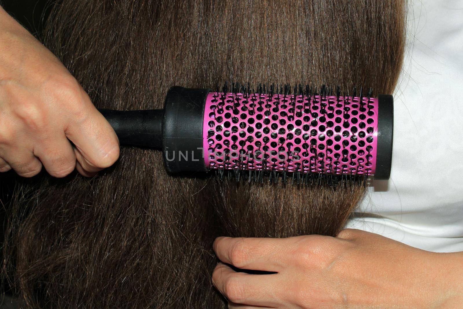 A girl with dark long hair combs her hair. Hair care. Hair loss problem.