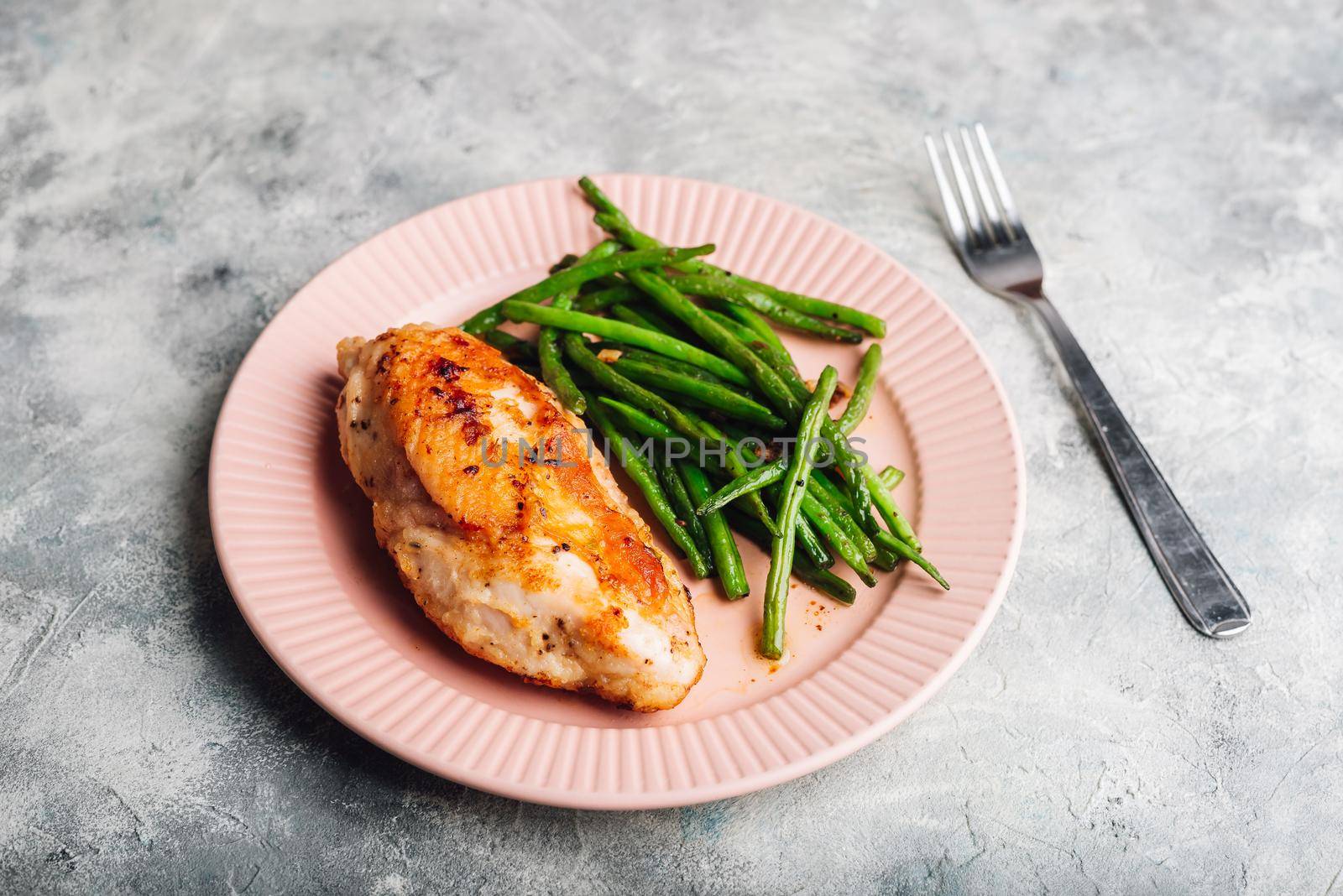 Crispy Oven-baked Chicken Breast Served on Plate with Green Beans Fried with Garlic and Thyme