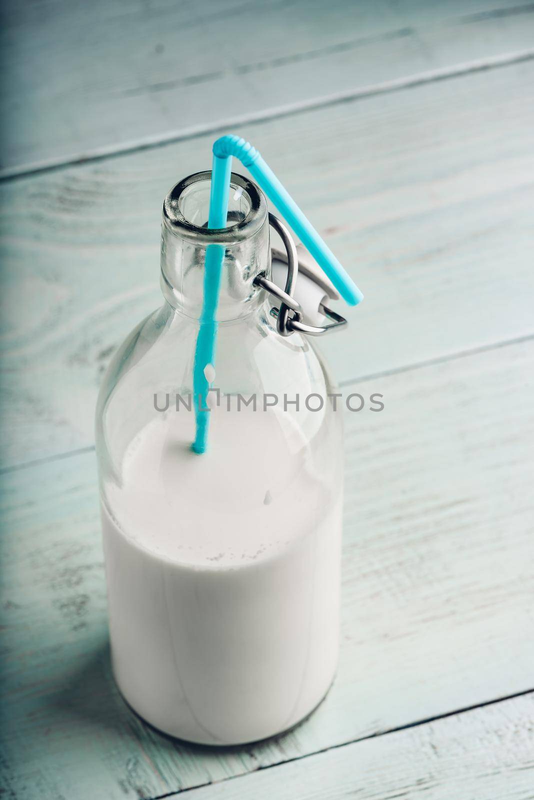 Almand milk in glass bottle with blue straw