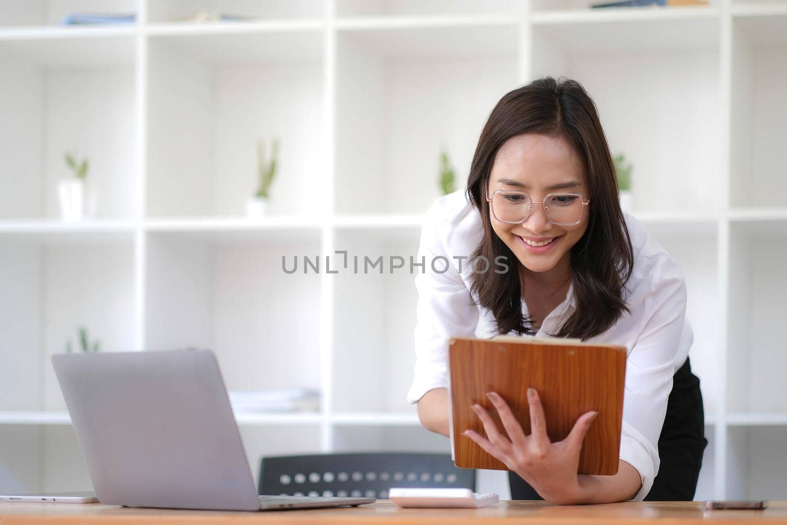 Happy young business woman entrepreneur using computer looking at screen working in internet sit at office desk, smiling hindu female professional employee typing email on laptop at workplace.