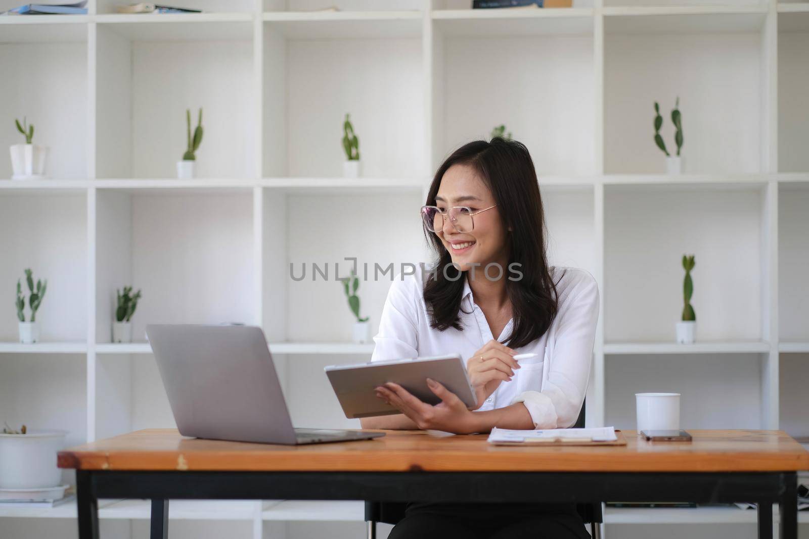 Beautiful woman Asian using digital tablet work at the office. by wichayada