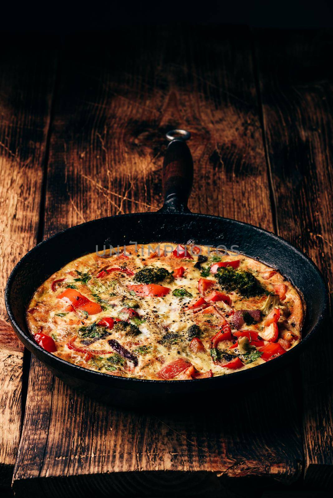 Vegetable frittata with broccoli, red bell pepper and red onion in cast iron pan