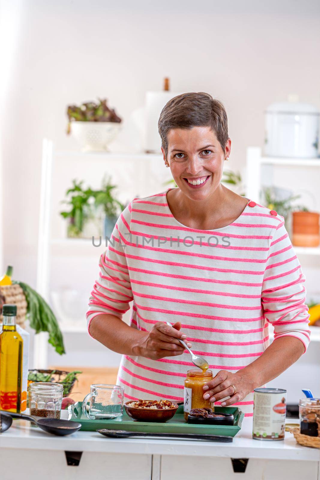 Young woman with a jar of honey to mix with cereals and other seeds.