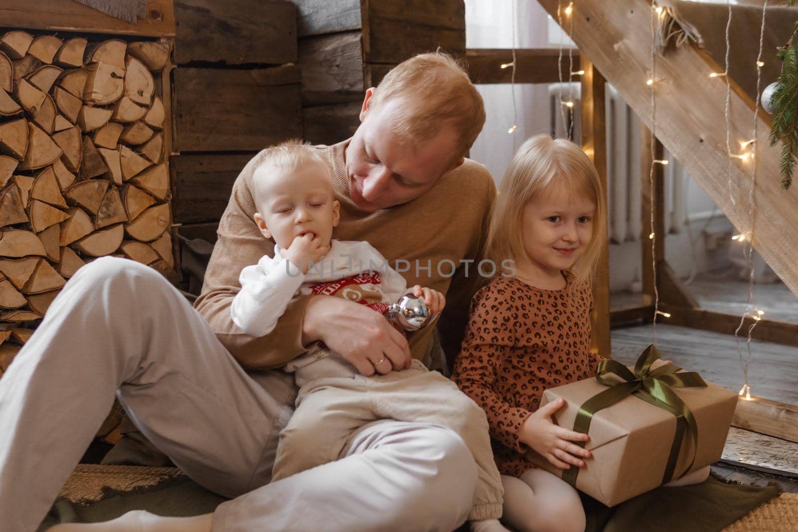 Dad and little brother and sister play on Christmas Eve in a beautiful house decorated for the New Year holidays. The concept of family holidays. by Annu1tochka