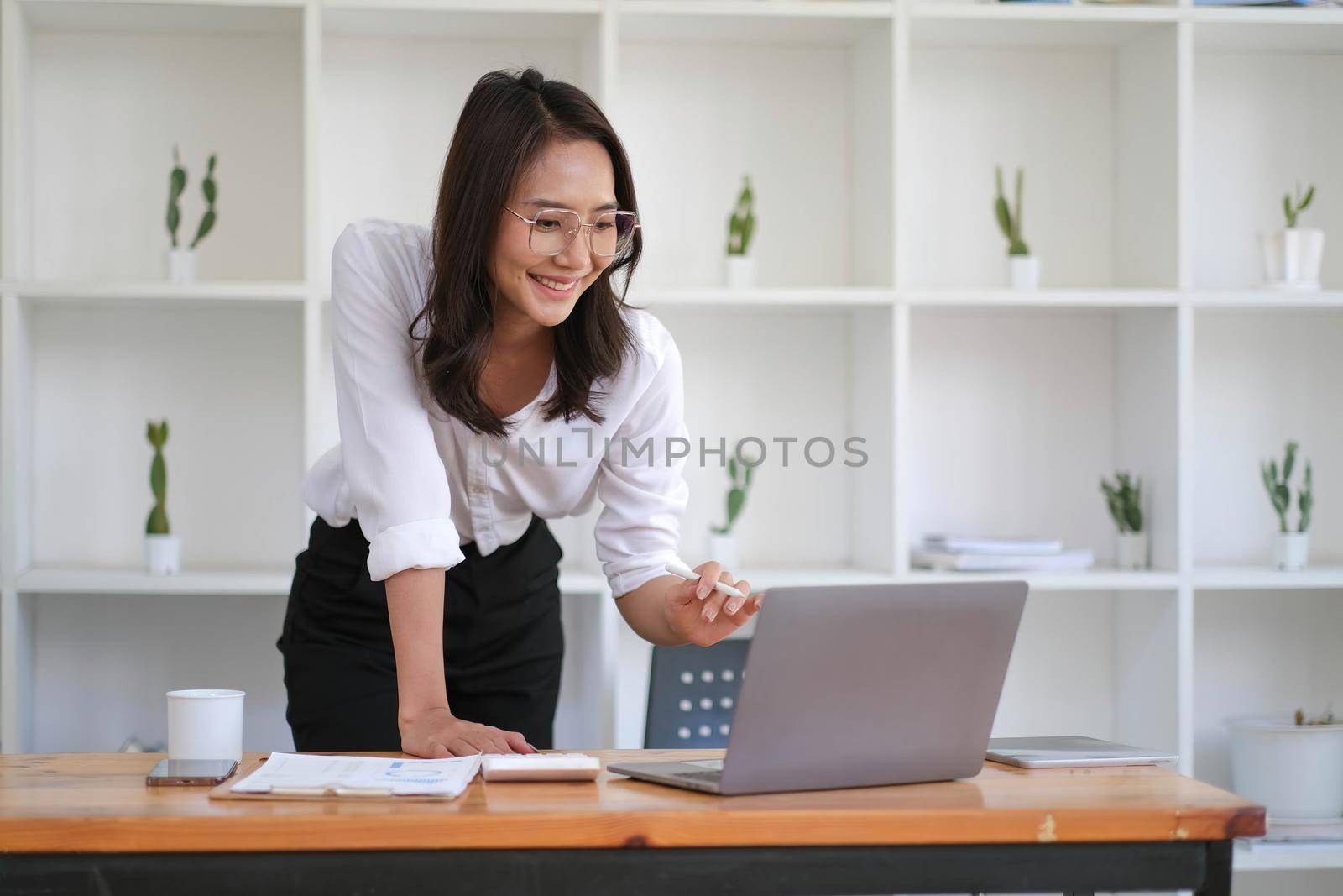 Portrait of smiling beautiful Asian businesswoman enjoy the idea sitting with laptop computer at office..