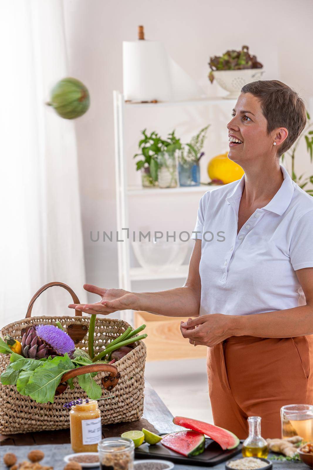 The woman plays with the round zucchini by throwing it into the air.