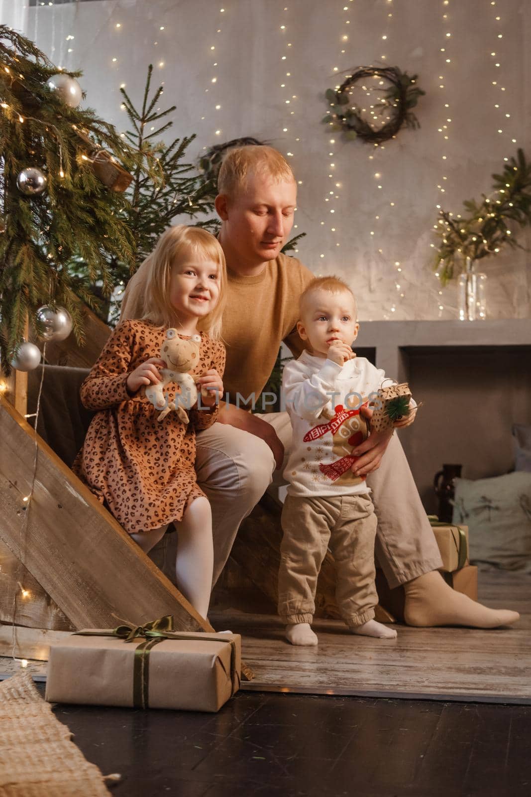 Dad and little brother and sister play on Christmas Eve in a beautiful house decorated for the New Year holidays. The concept of family holidays