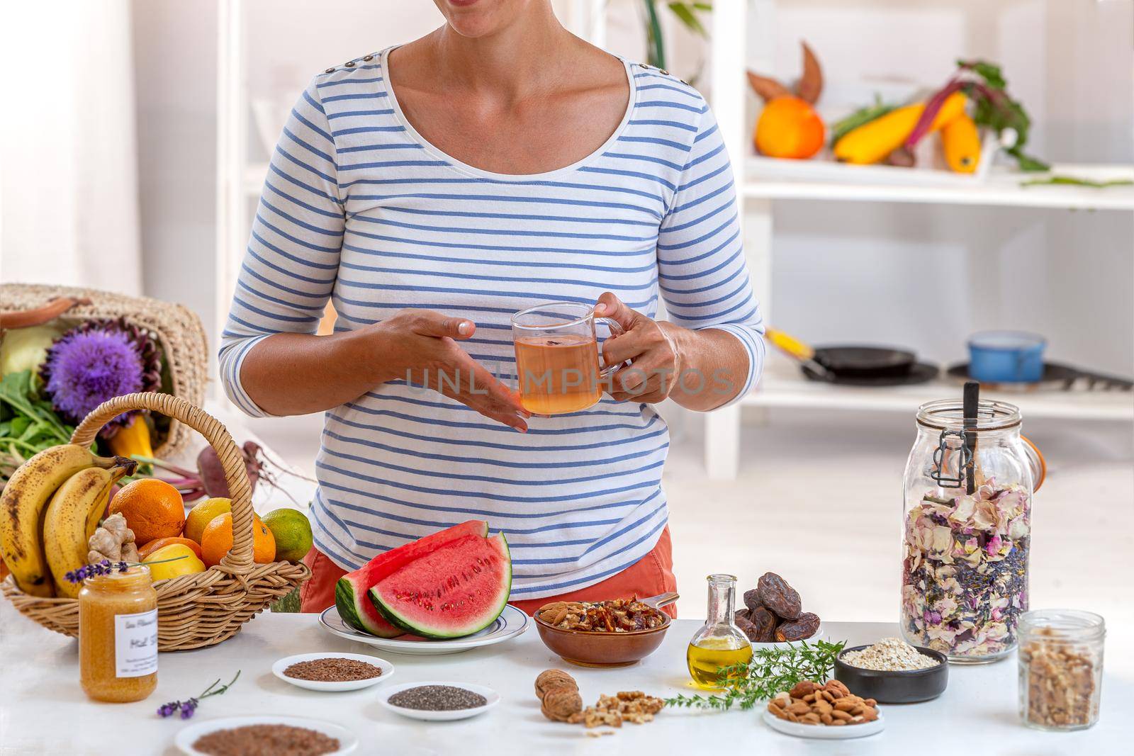 Woman, face cut a cup of tea in hand, surrounded by cereals, fresh fruit and dried fruit, honey,