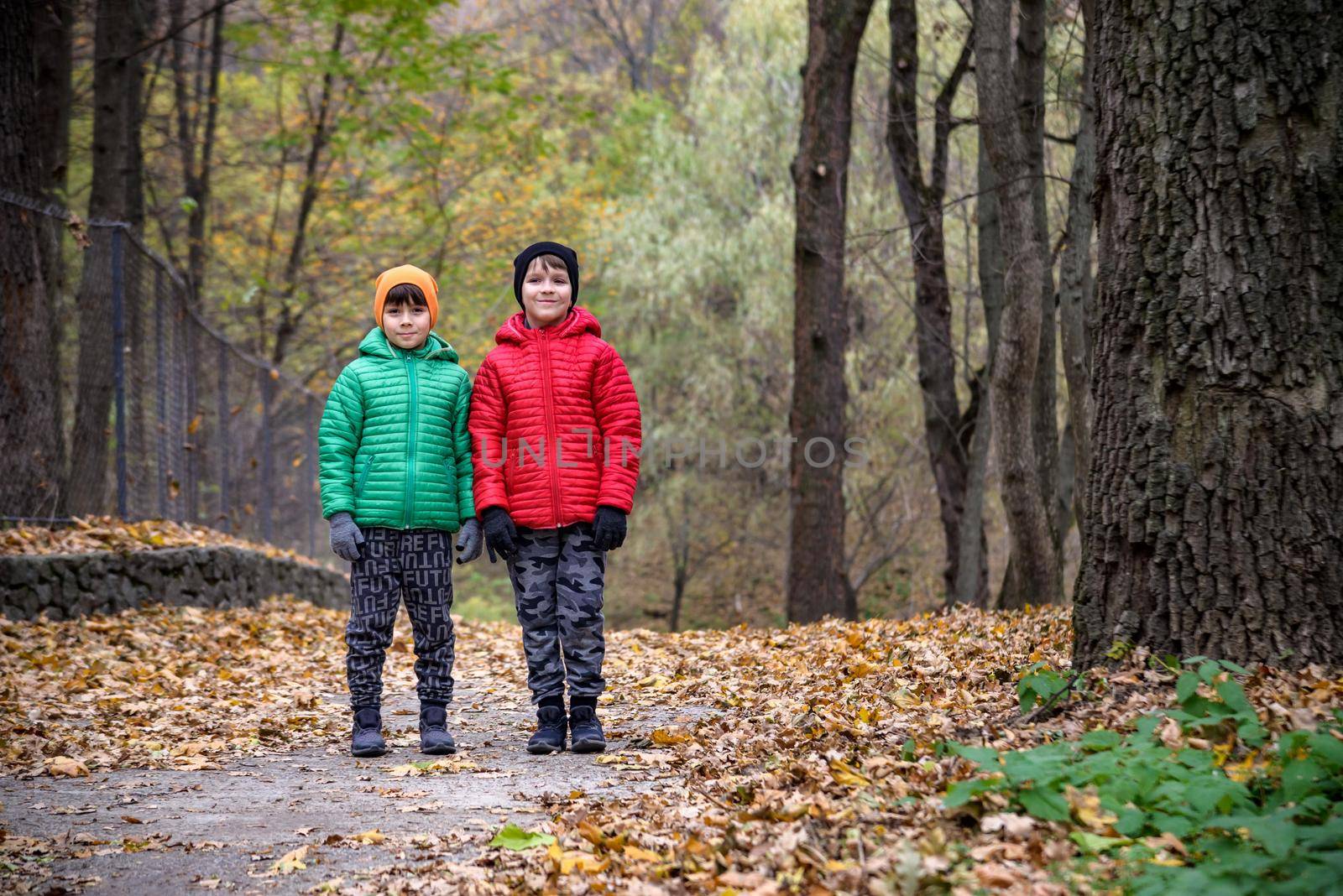 Two children boy and sibling brother in warm hats with backpacks by Kobysh