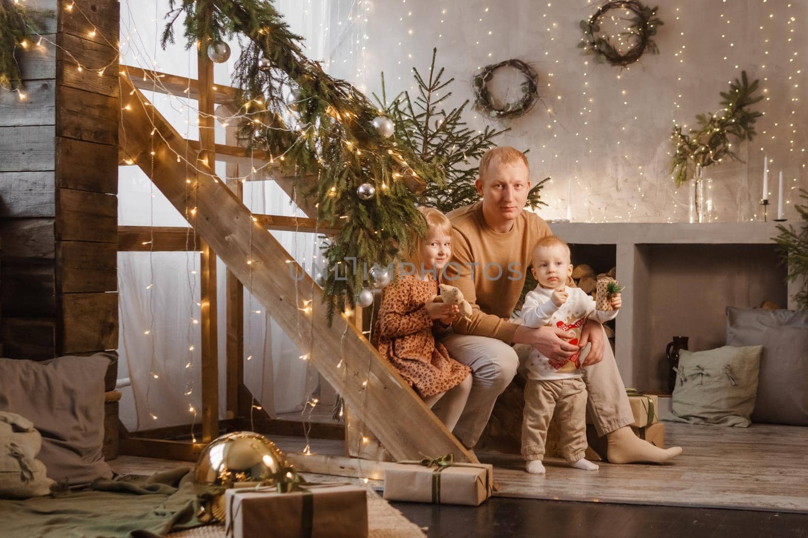 Dad and little brother and sister play on Christmas Eve in a beautiful house decorated for the New Year holidays. The concept of family holidays