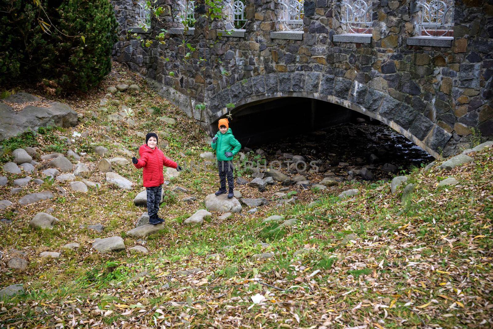 Portrait of two boys kid a walk under a brick bridge and looking by Kobysh