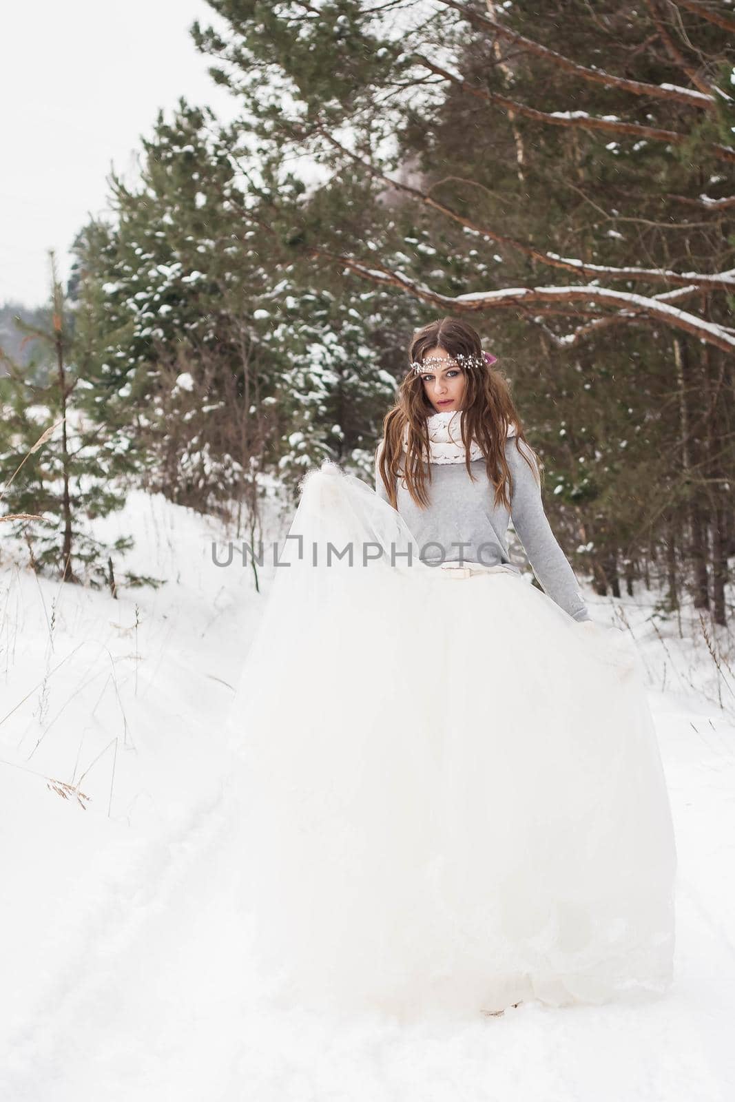 Beautiful bride in a white dress with a bouquet in a snow-covered winter forest. Portrait of the bride in nature by Annu1tochka