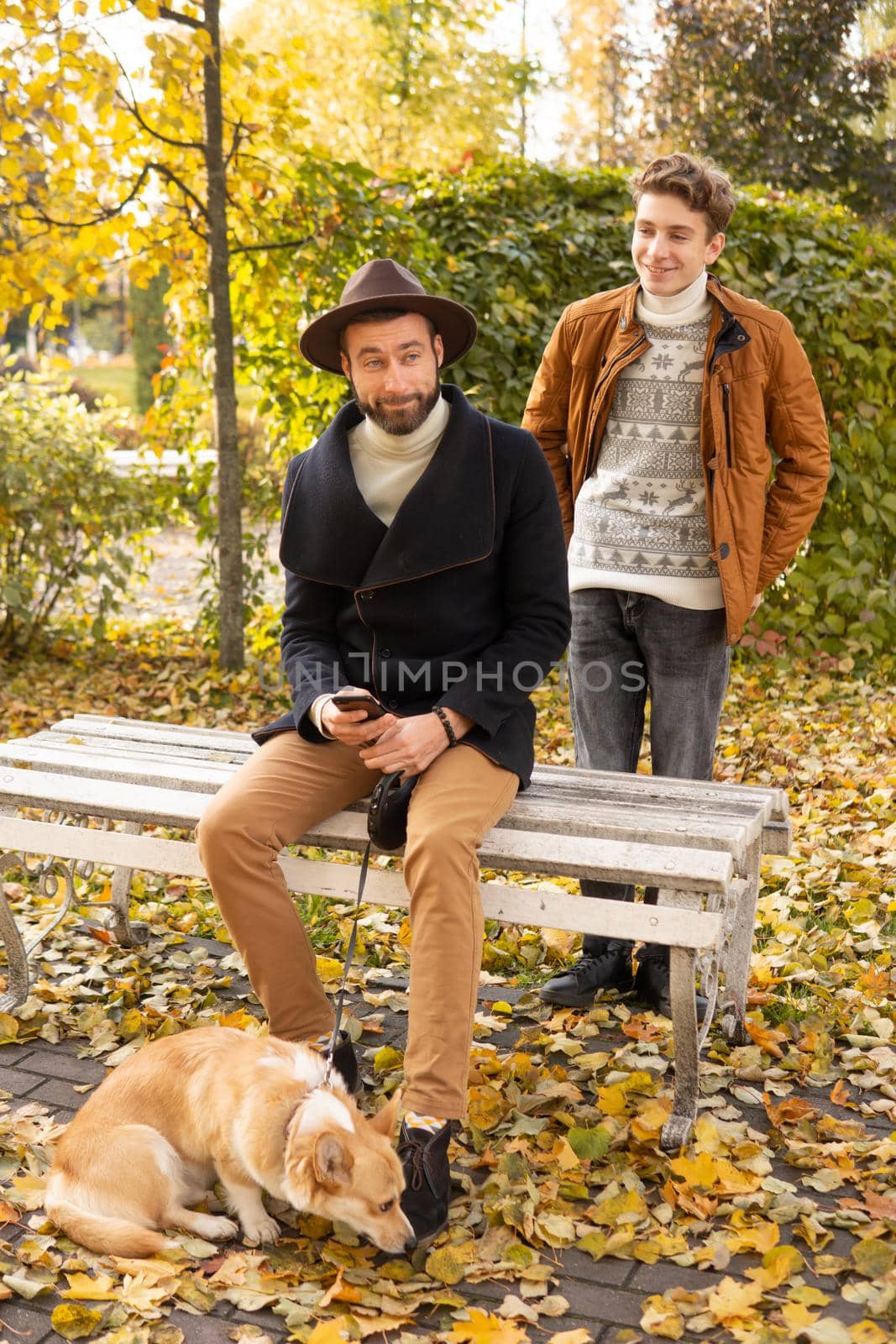 Father and son with a pet on a walk in the autumn park.