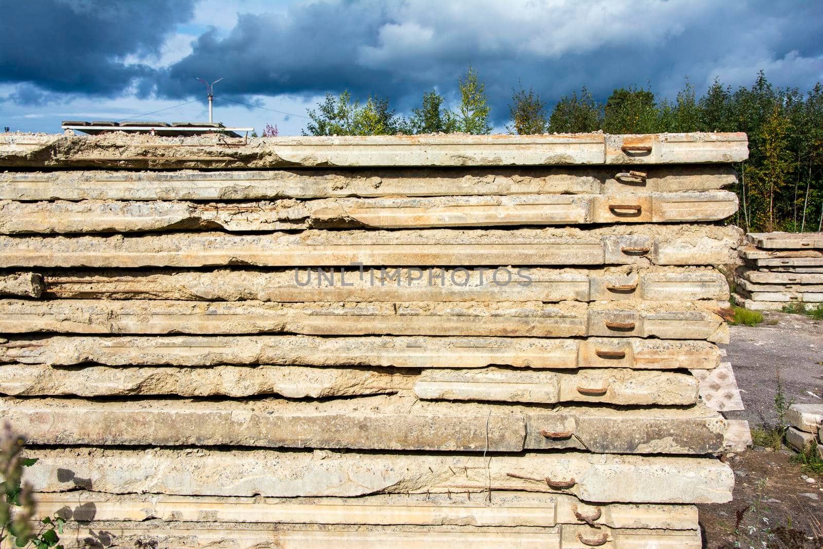 a stack of old dismantled concrete road slabs. Old dirty reinforced concrete road slabs stacked for later use. High quality photo