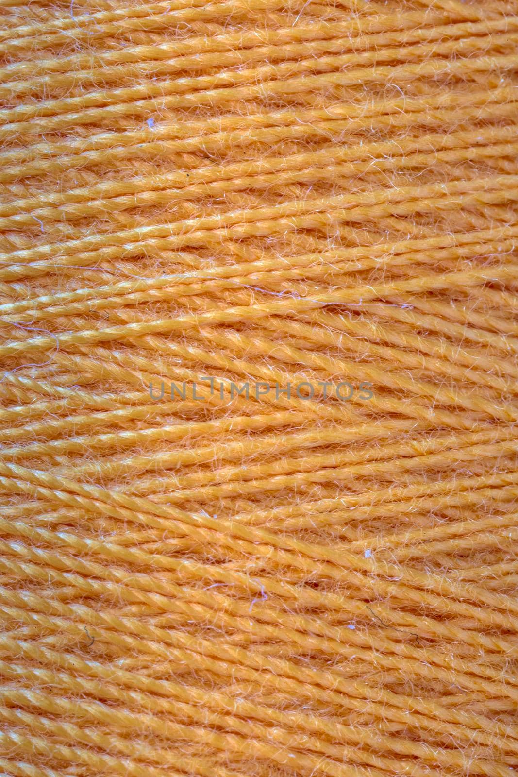 The macro texture of orange cotton thread on bobbin, close-up,