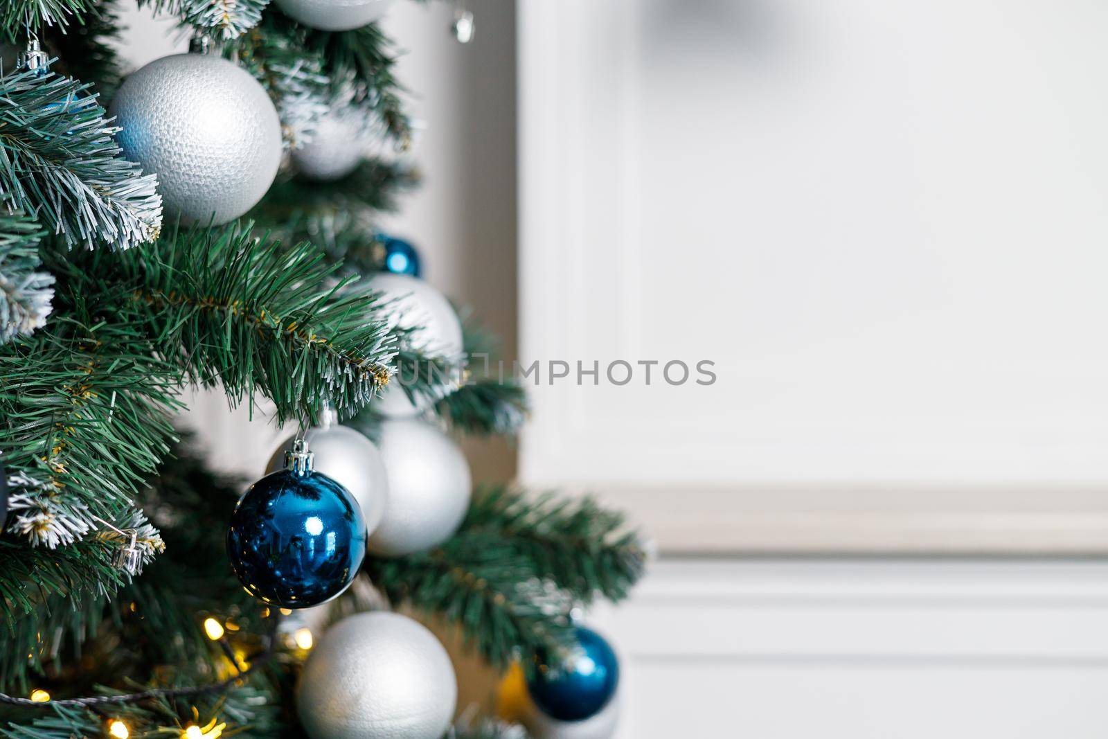 Christmas tree with blue and silver toys. Festively decorated Christmas tree with garlands. Symbol of the new year.