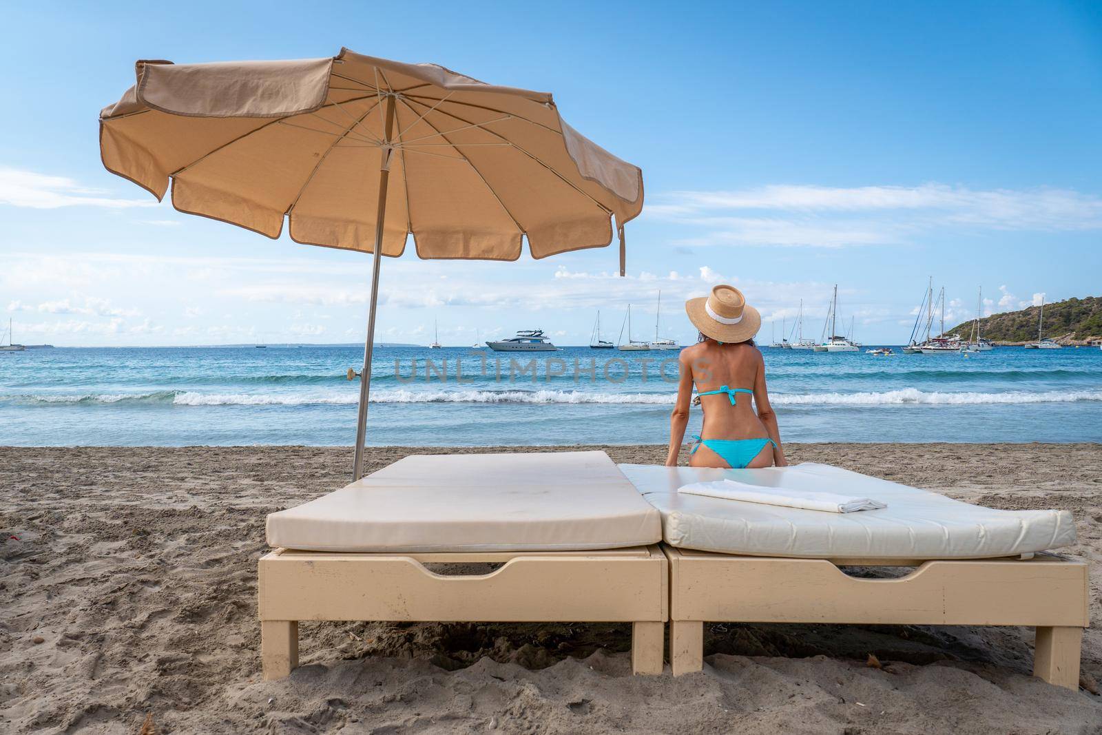 Lonely woman in bikini looking at the sea on a bed