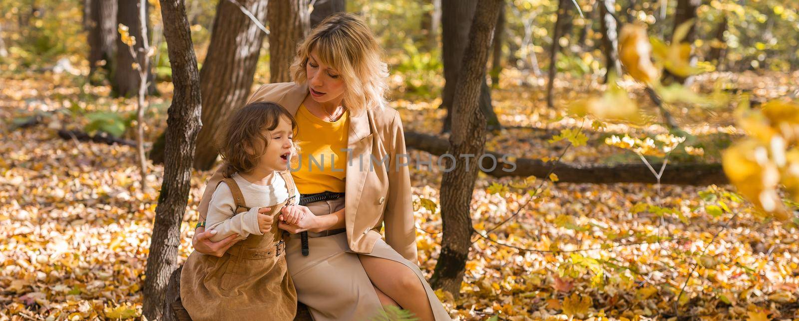Banner mother comforting her crying little girl in autumn nature copy space. Emotions and family concept. by Satura86